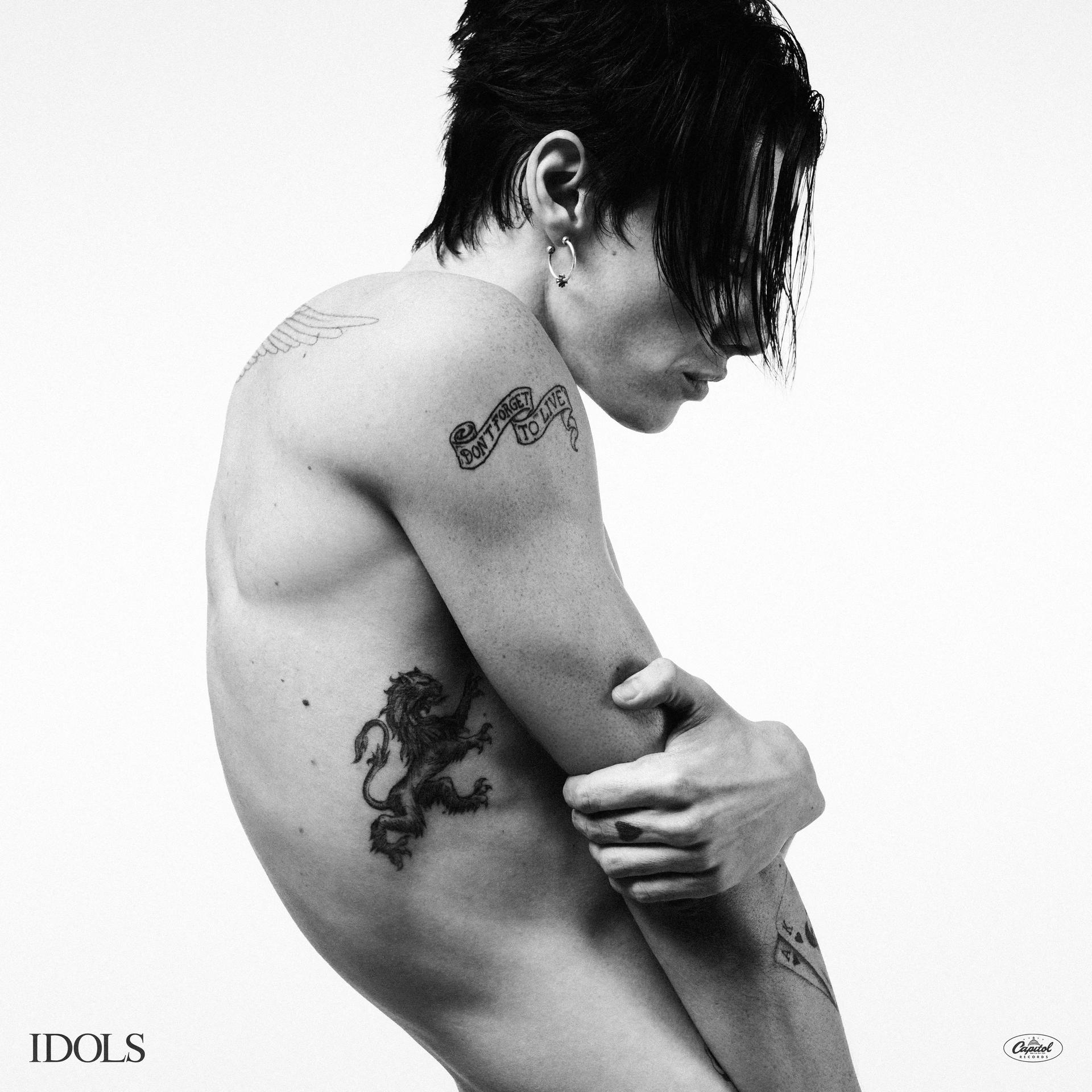 Schwarz-Weiß-Foto eines Mannes ohne Hemd mit Tattoos, der nach unten schaut.