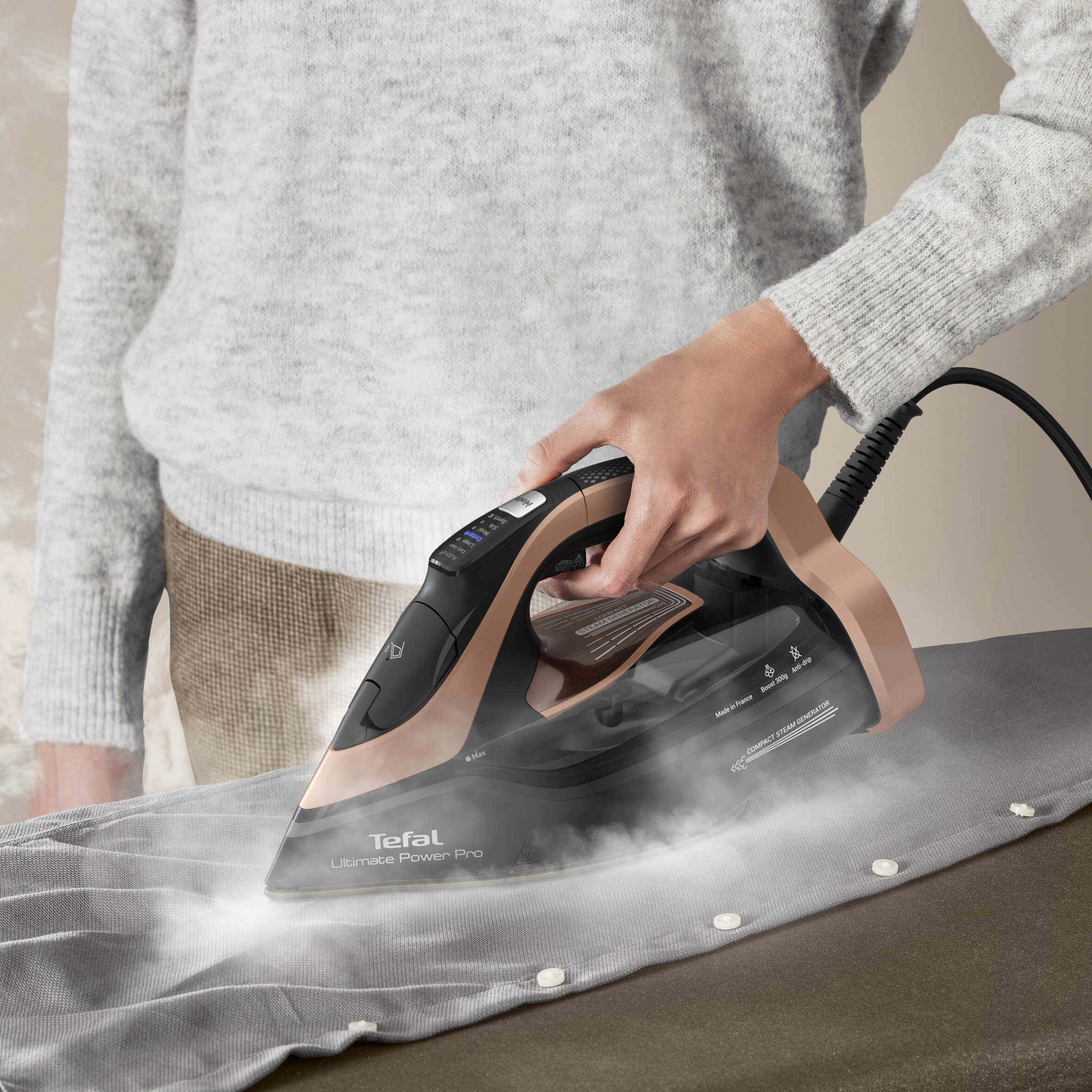 Osoba prasująca szarą koszulę żelazkiem parowym.