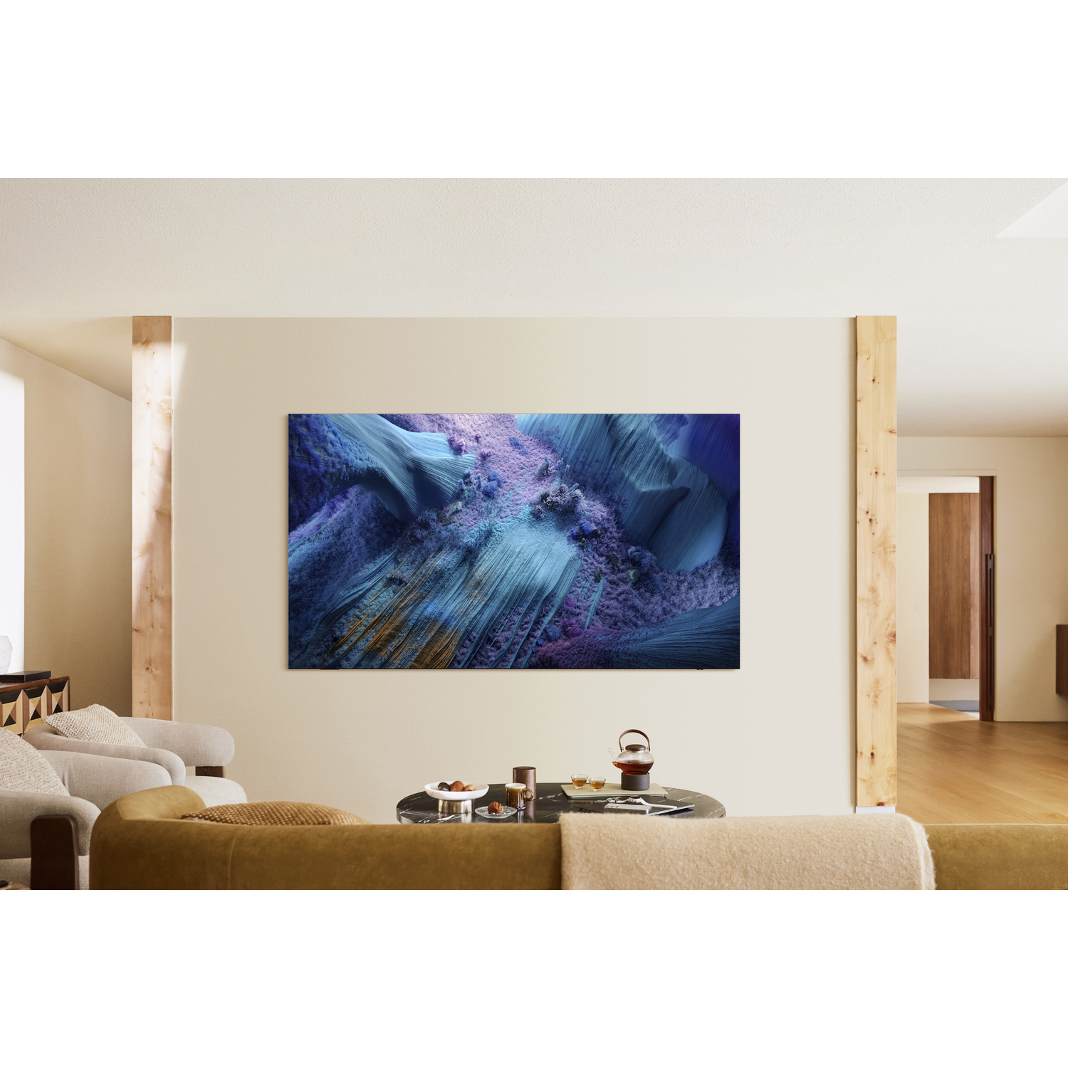 A large TV displays a blue and purple abstract landscape.  The TV is mounted on a beige wall.