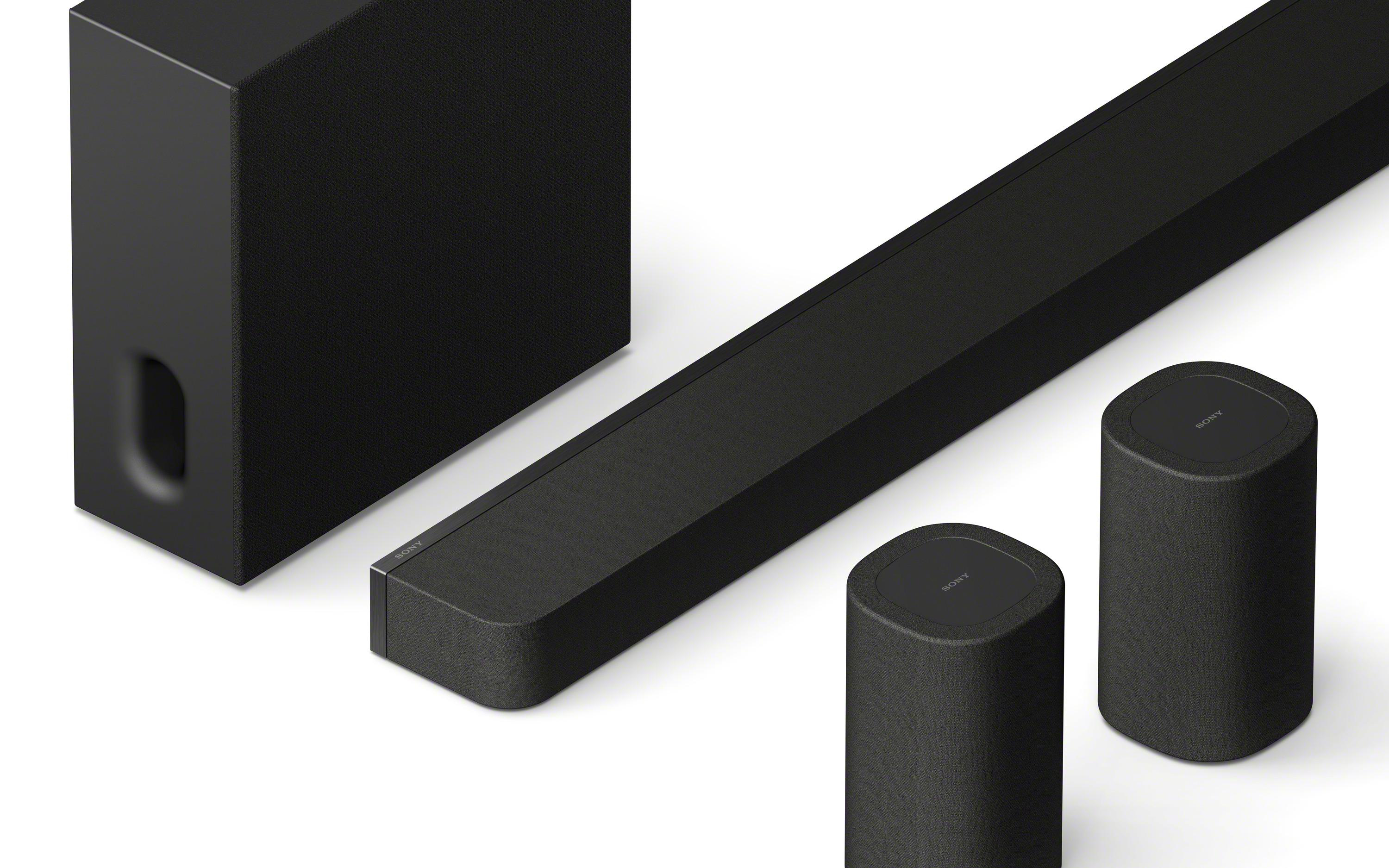 Ein schwarzes Soundsystem-Setup: Soundbar, Subwoofer und zwei zylindrische Lautsprecher.