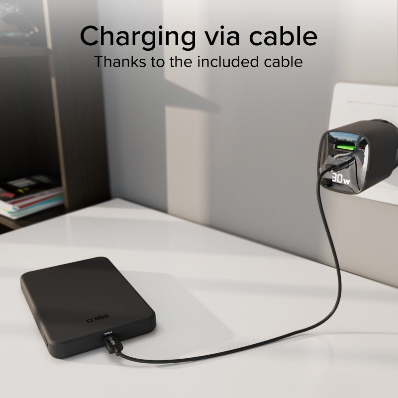 Czarny power bank podłączony do ładowarki na białym stole. Tekst: Ładowanie za pomocą kabla.