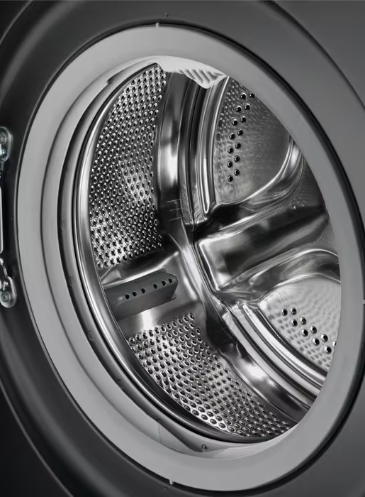 Zbliżenie wnętrza bębna pralki. Stal nierdzewna z perforacjami, ciemnoszara rama.