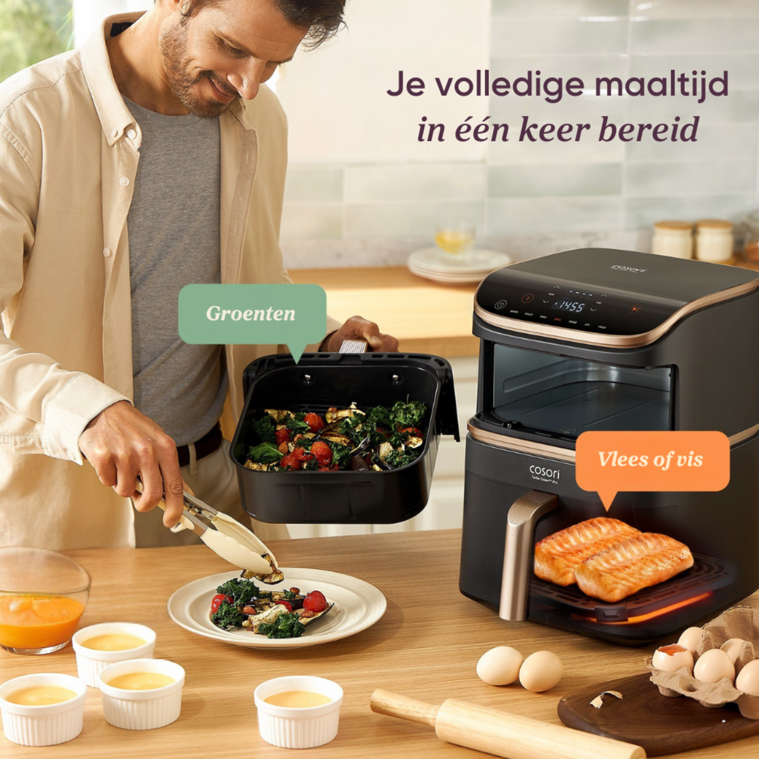 A man prepares food using an air fryer. The fryer has salmon and vegetables. Eggs, juice, and utensils are on the table.