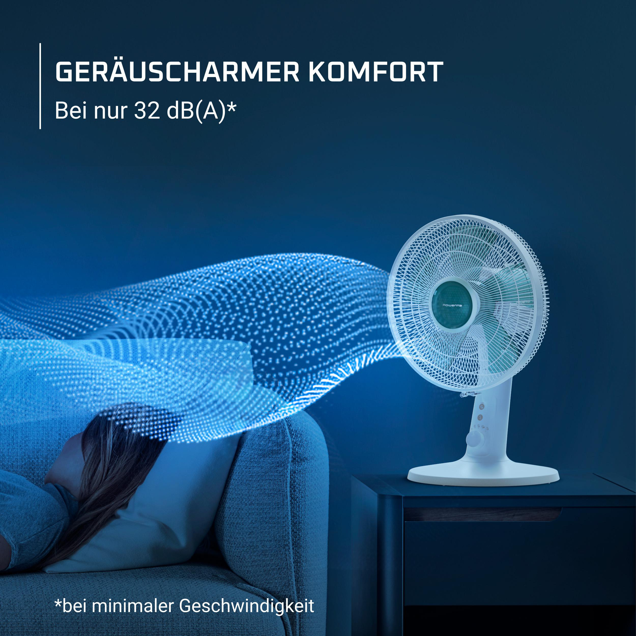 Fan steht auf einem Nachttisch, der Mann schläft auf der Couch.