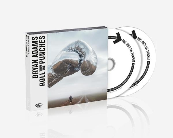 Albumcover mit zwei CDs: Silberner Boxhandschuh schwebt, Figur auf Straße. 'Roll with the Punches', Bryan Adams.