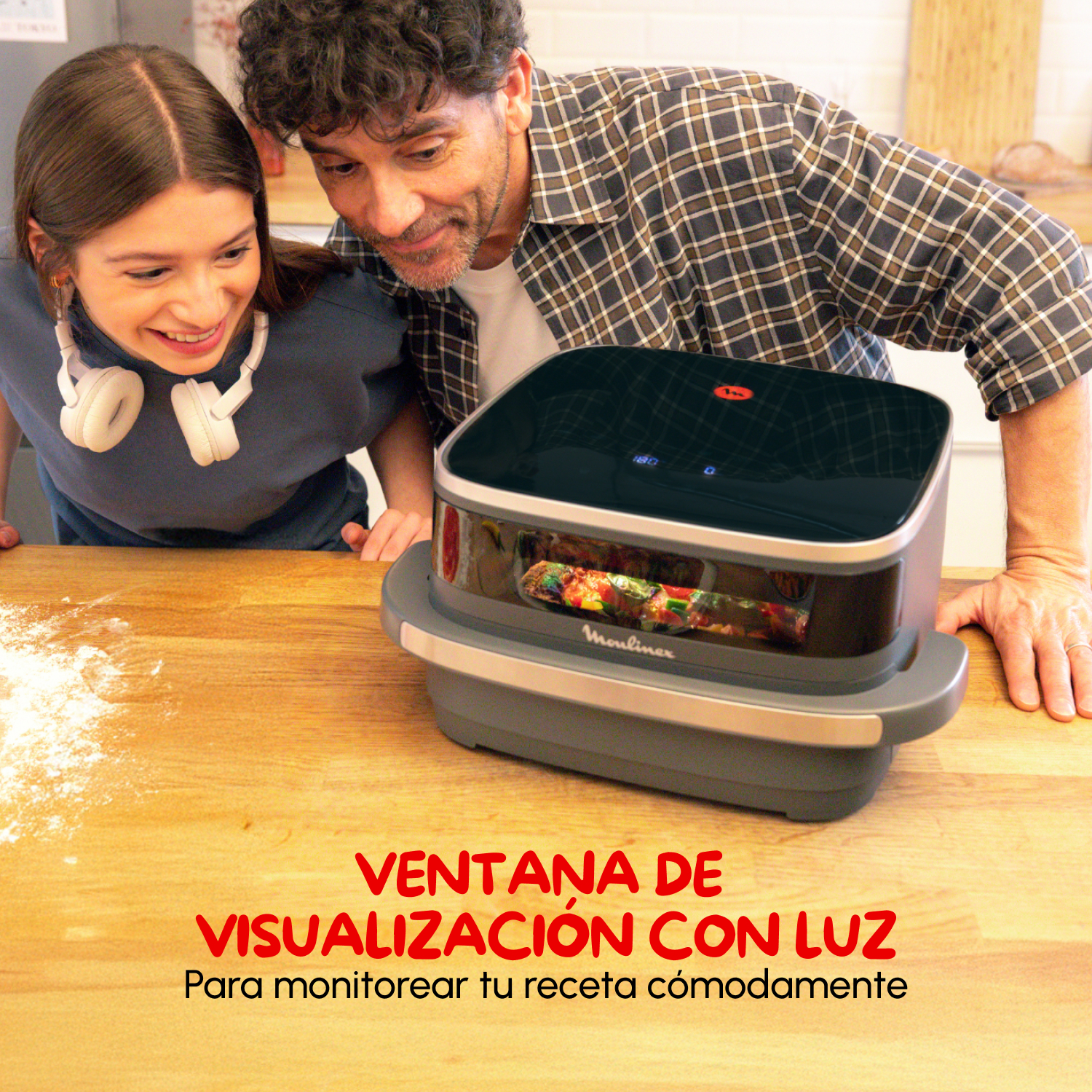 Dos personas observan comida cocinándose dentro de una freidora de aire negra y gris. Un texto dice: "VENTANA DE VISUALIZACIÓN CON LUZ".