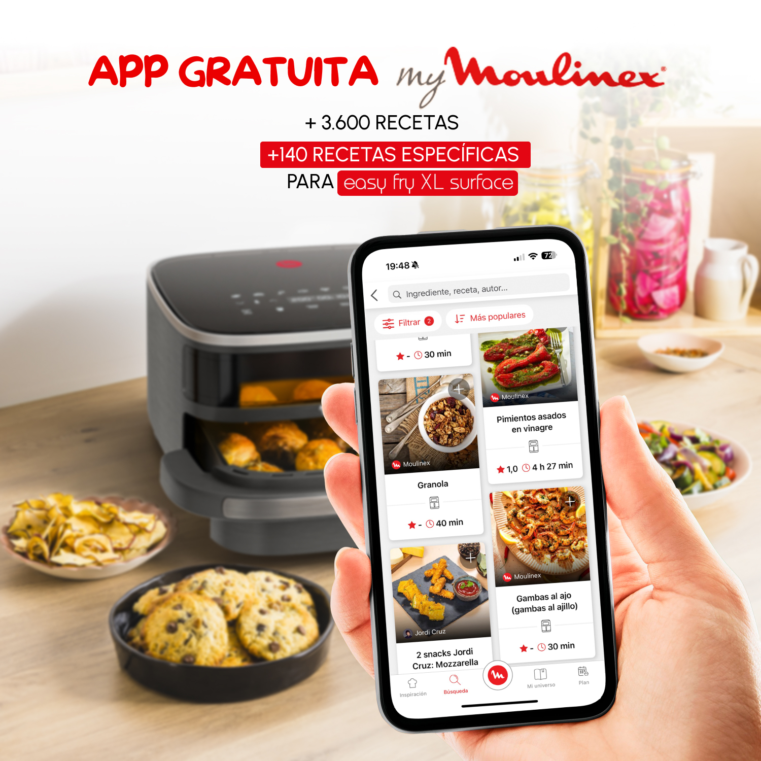 Una persona sostiene un teléfono con una aplicación de cocina abierta. Una freidora de aire y varios platos están en el mostrador.