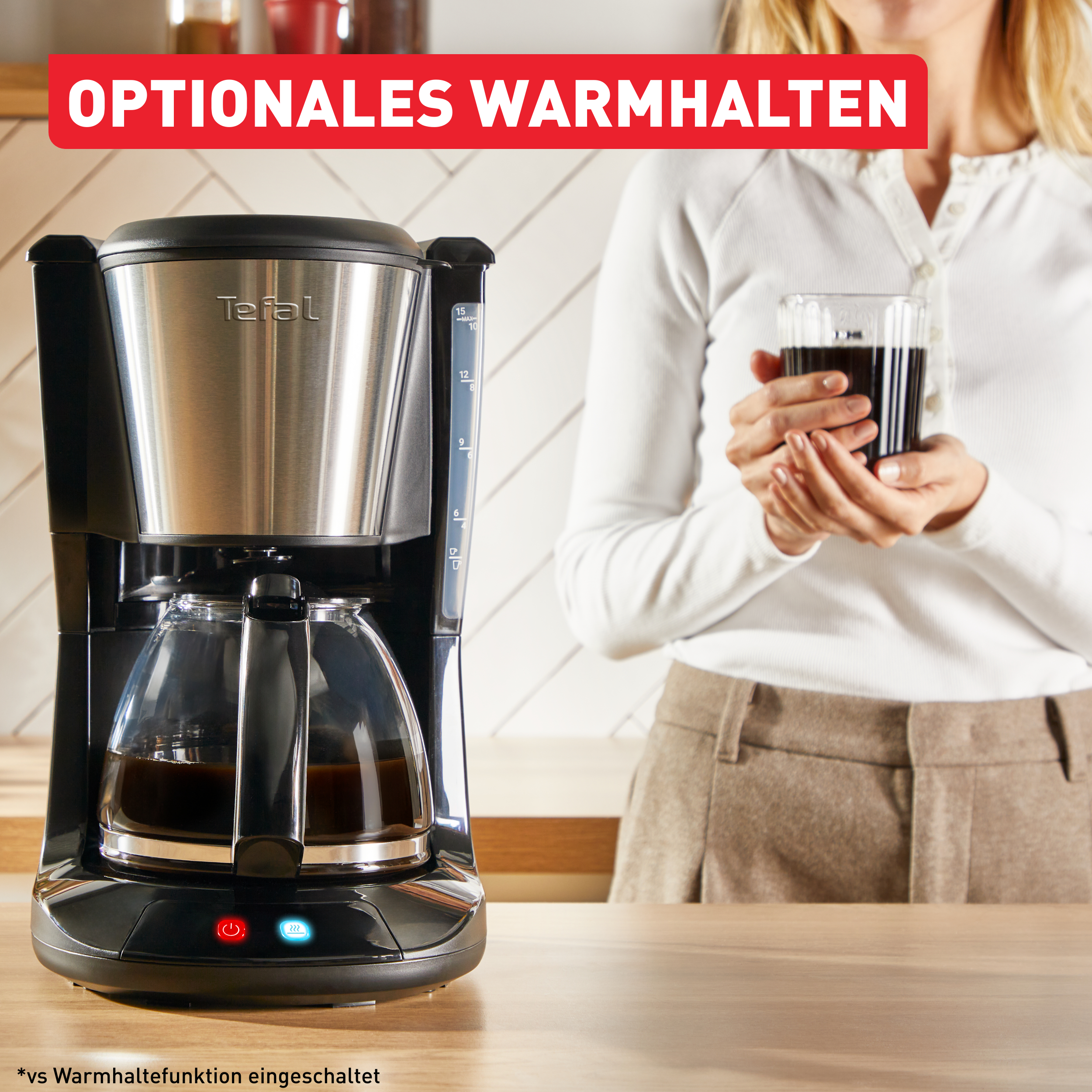 Kaffeemaschine mit einer Glaskaraffe, die mit Kaffee gefüllt ist. Eine Person hält eine Tasse. Roter Text sagt optional warmhalten.