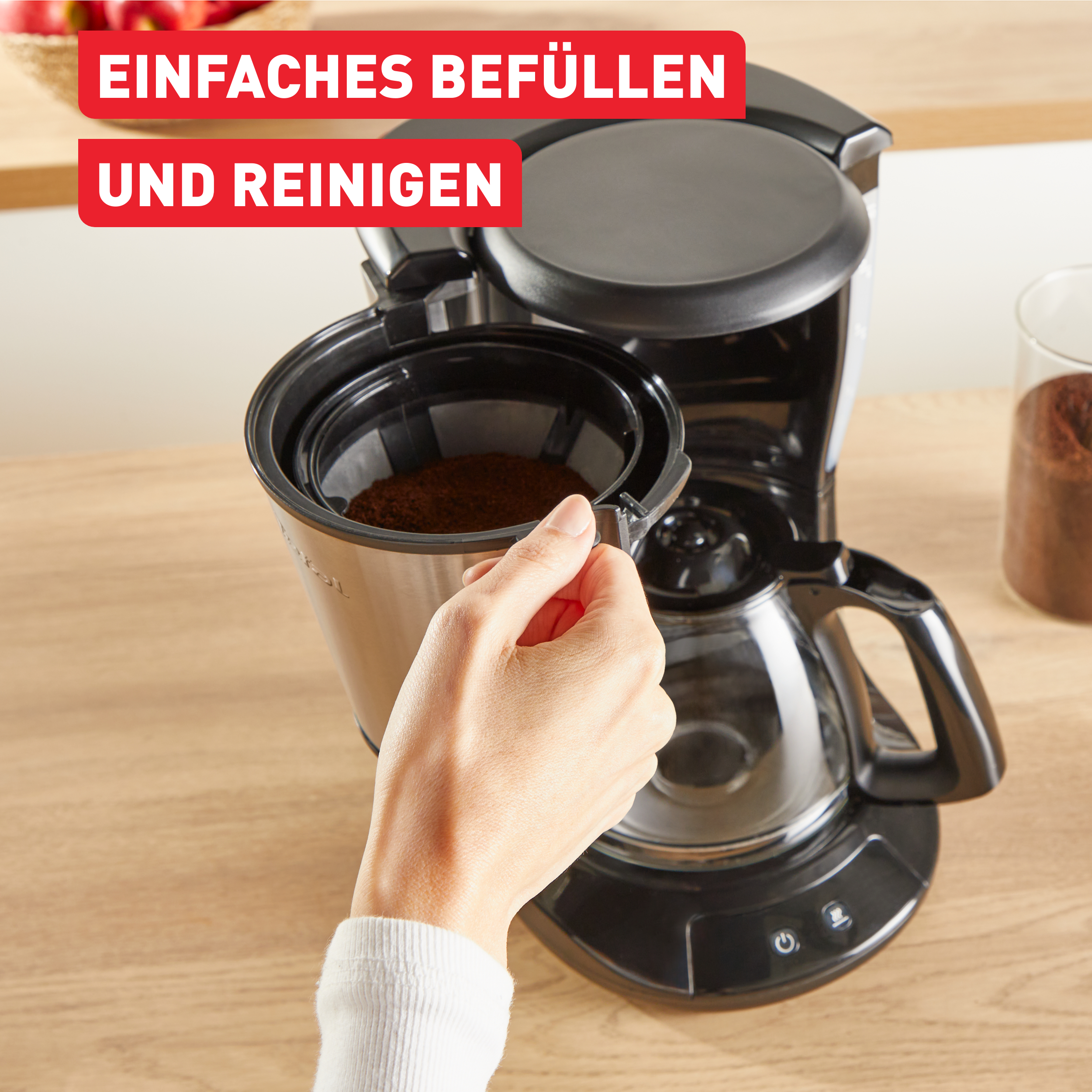 Eine Hand gibt Kaffeepulver in einen Filter in der Kaffeemaschine. Roter Text sagt einfach zu befüllen und zu reinigen.
