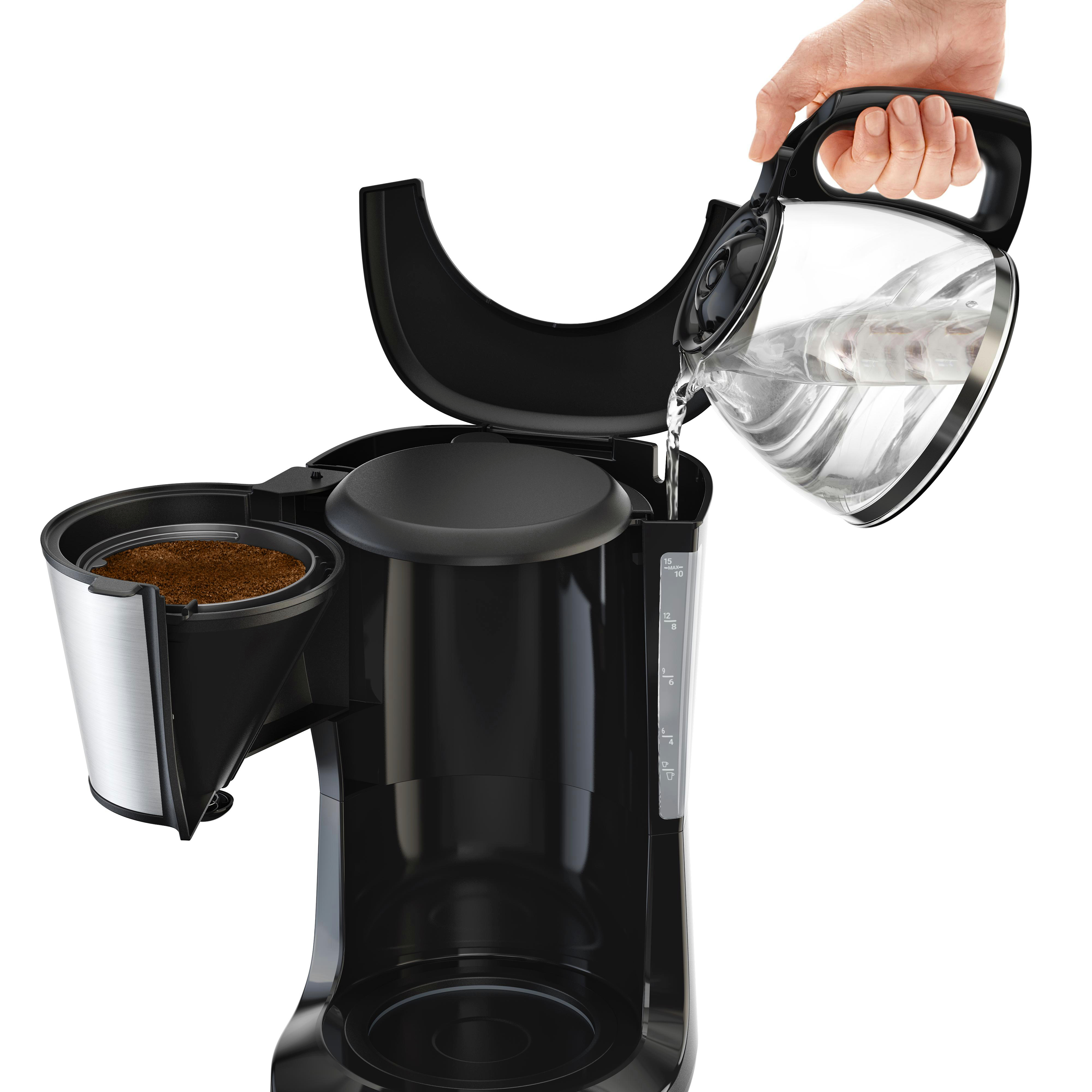 Eine Person gießt Wasser aus einem Krug in die Kaffeemaschine. Der Filter enthält Kaffeesatz.