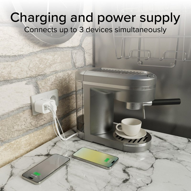 Adapter ładujący urządzenia na marmurowym blacie. Obecny jest również ekspres do kawy i dwa telefony.