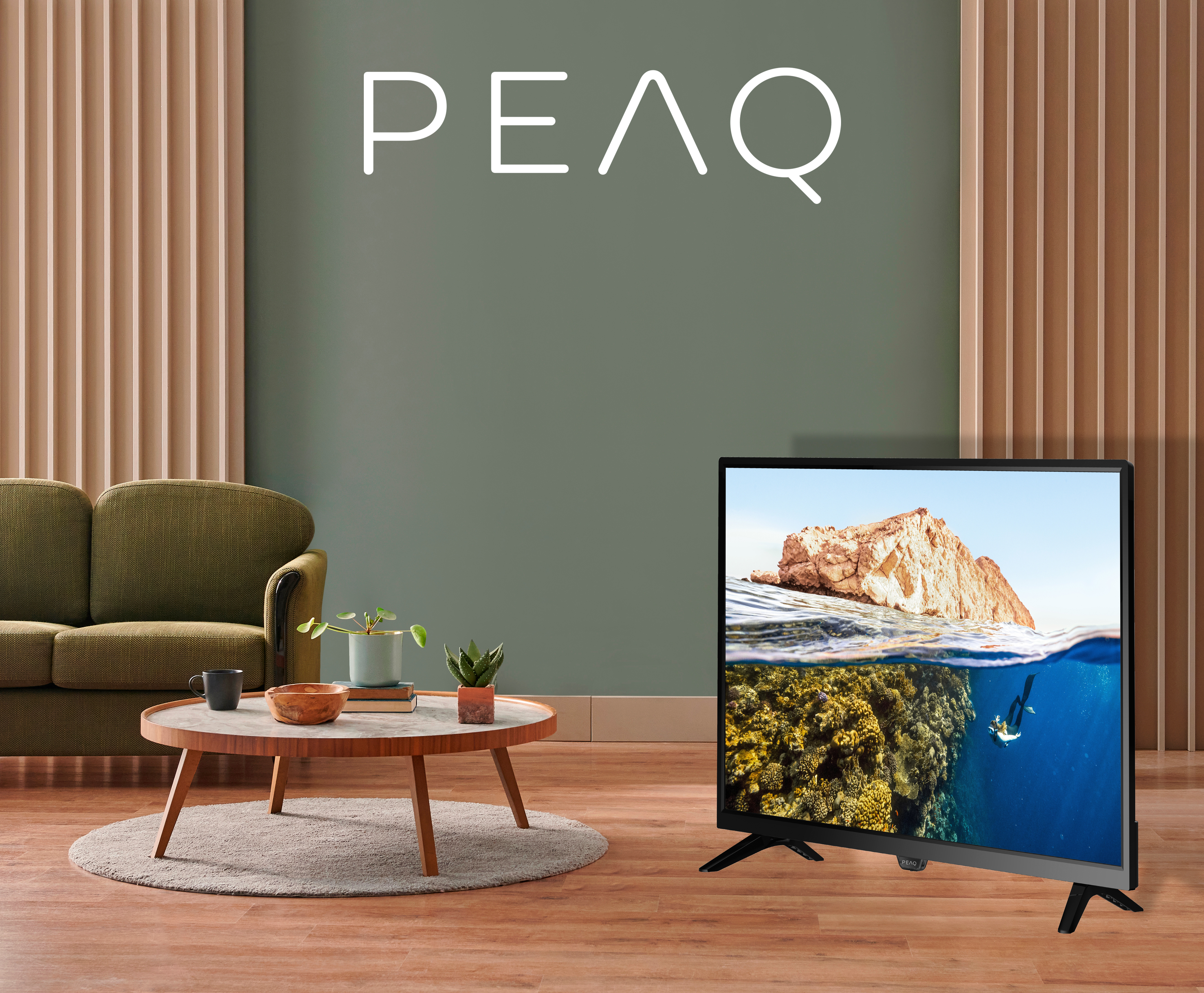 Sualtı sahnesi gösteren bir TV bulunan oturma odası. Ön planda bir kanepe, sehpa ve bitkiler var.