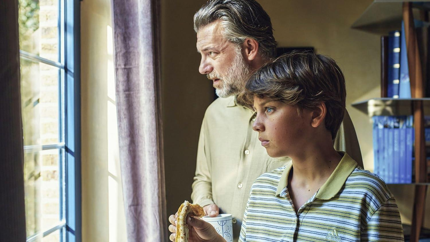 Ein Vater und Sohn schauen aus dem Fenster, halten ein Sandwich.