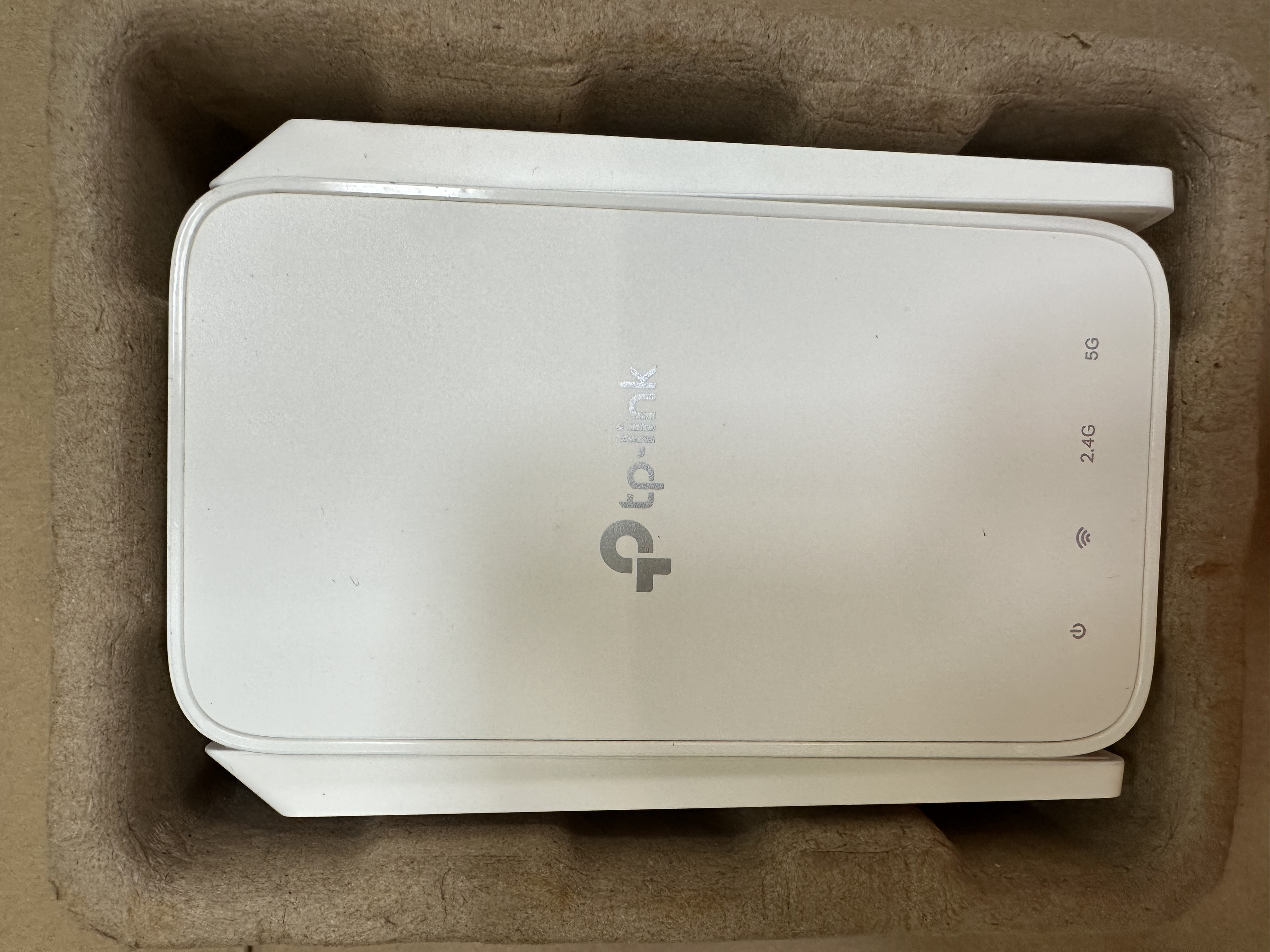 Widok z góry na biały router TP-Link w kartonowym pudełku.