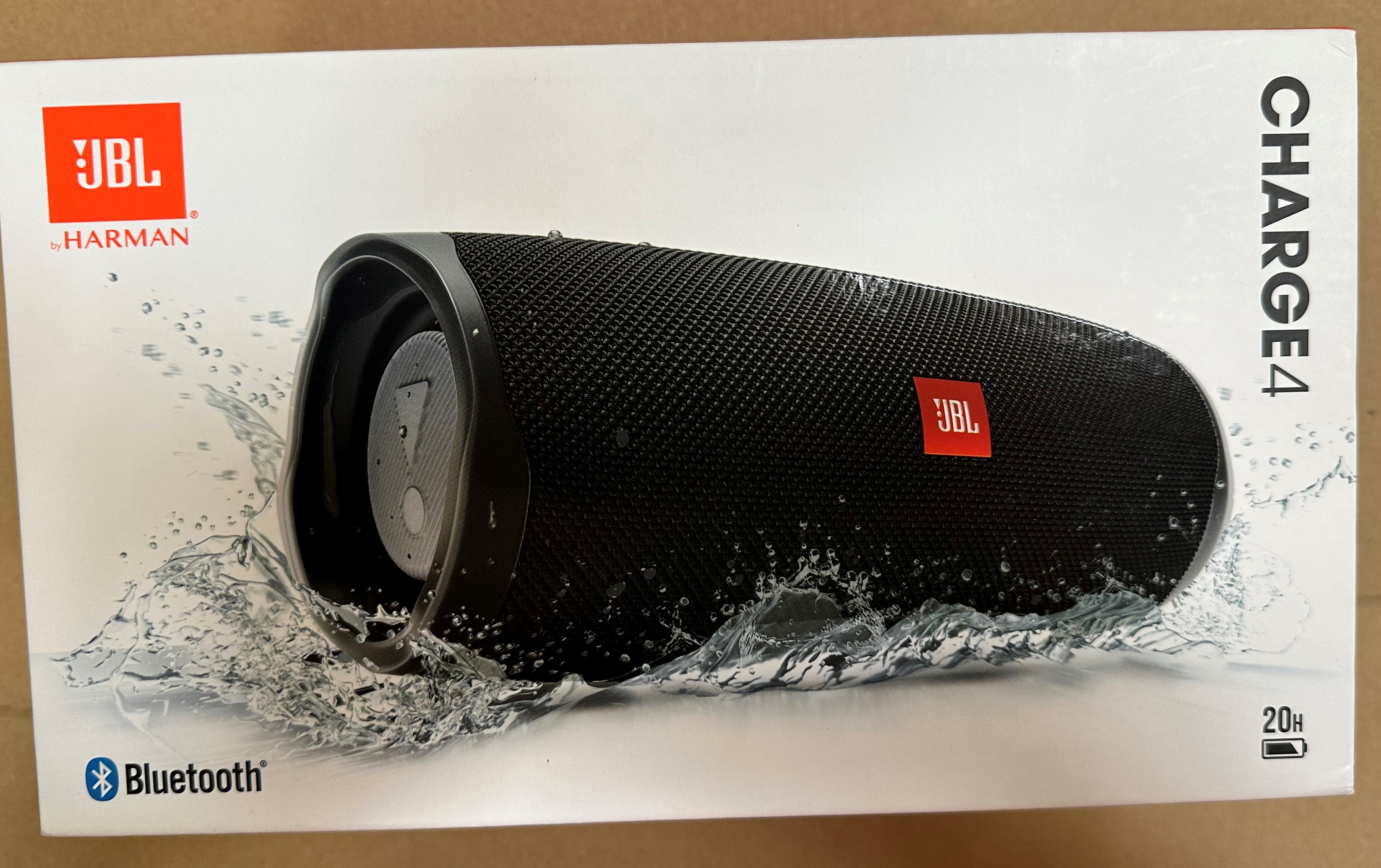 Pudełko głośnika JBL Charge 4. Czarny głośnik z logo JBL. Widoczne rozpryski wody i ikona Bluetooth.