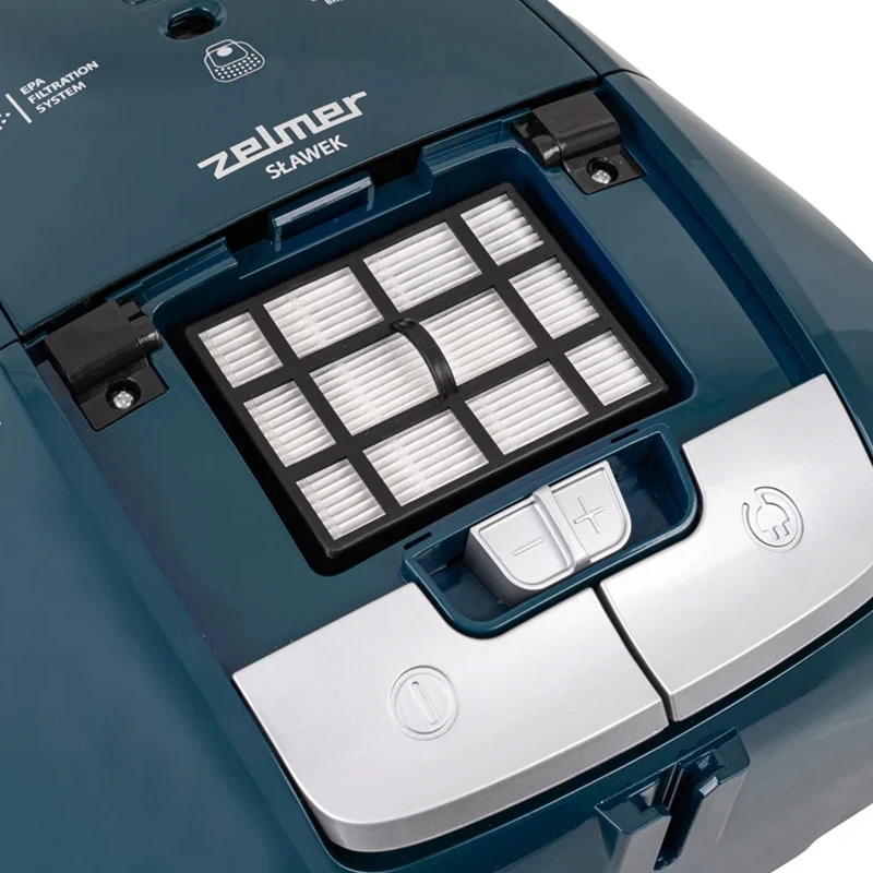 Otwarta komora filtra turkusowego odkurzacza, pokazująca filtr i szczegóły komory.