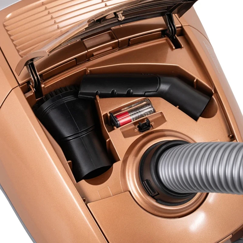 Złoty odkurzacz z akcesoriami przechowywanymi w środku. Zawiera nasadki i baterię.