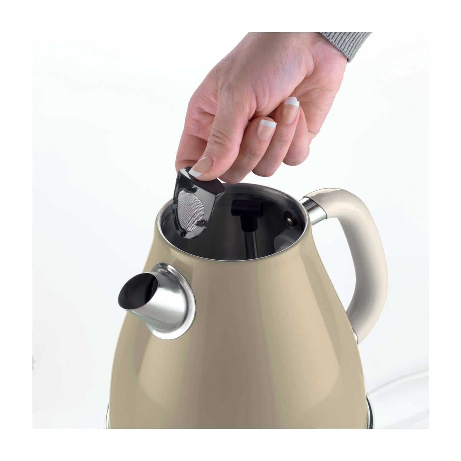 Una persona che mette un infusore di tè in un bollitore beige.