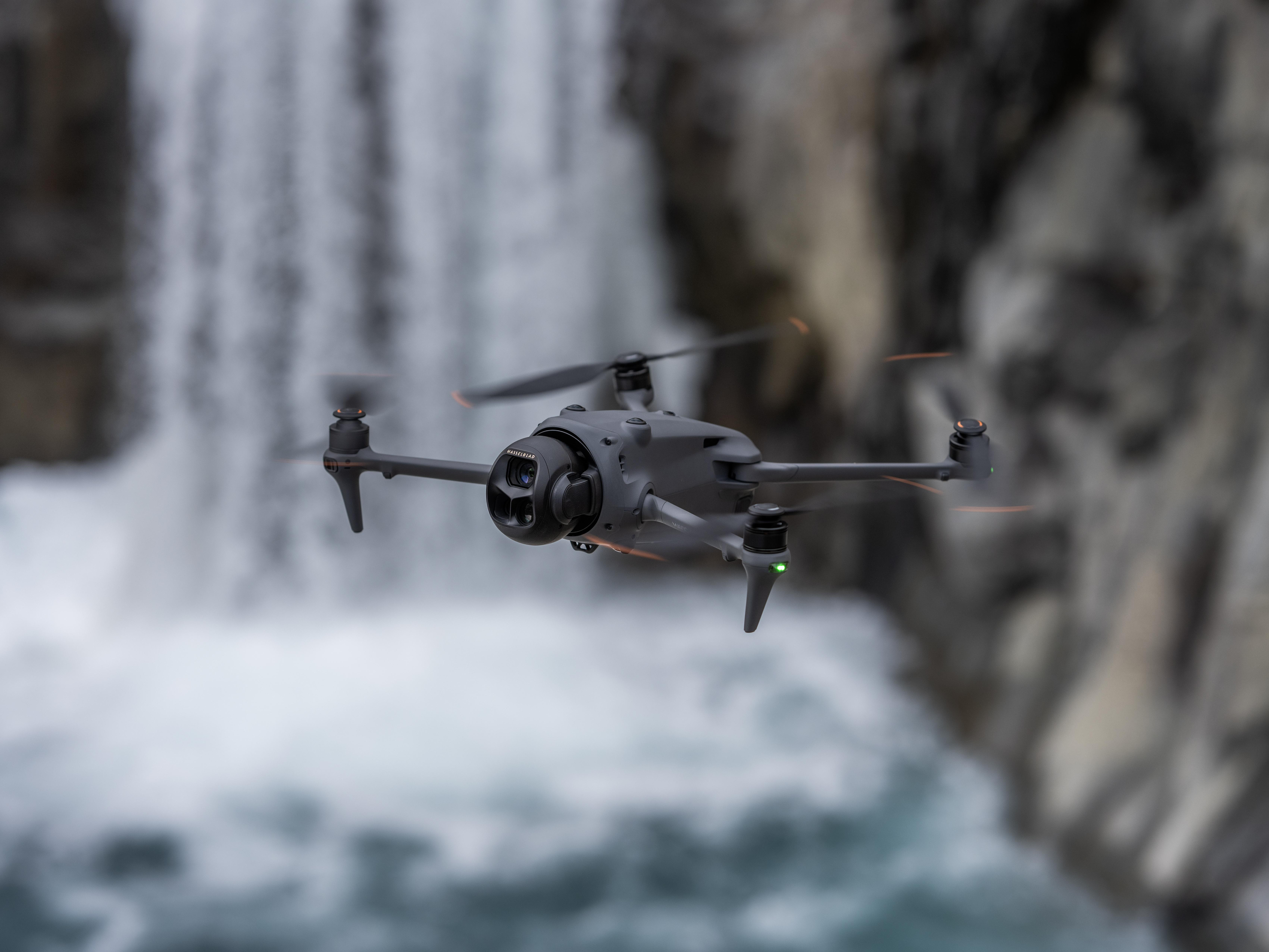 Drohne im Flug in der Luft vor einem Wasserfall, verschwommener Hintergrund.