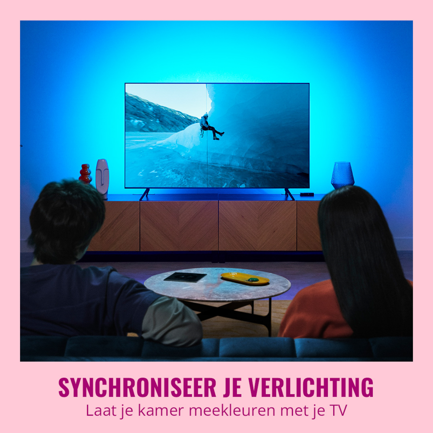 Two people watching TV. The screen shows a mountain climber. Pink background.