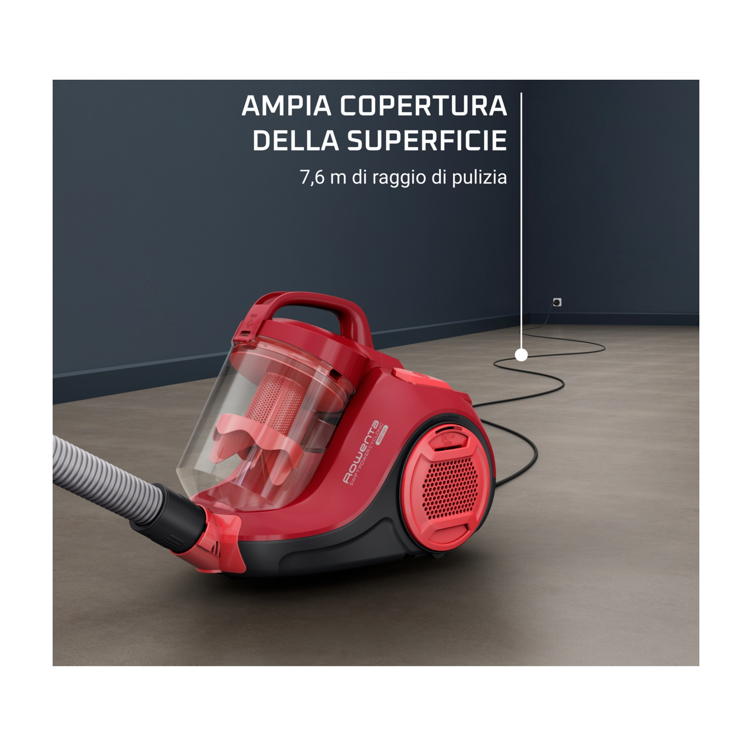 Aspirapolvere rosso su pavimento marrone, con tubo grigio. Sullo sfondo un muro scuro.