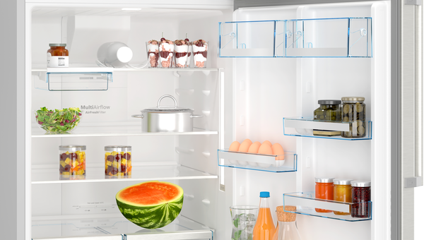 İçinde yiyecekler olan açık buzdolabı. Salata, kavanozlar, karpuz, tencere, tatlılar ve yumurtalar raflarda ve kapıda görünüyor.