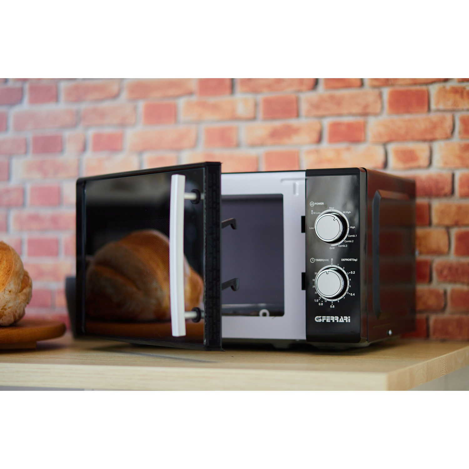 Forno a microonde nero su una superficie di legno, con la porta aperta e pane visibile all'interno.