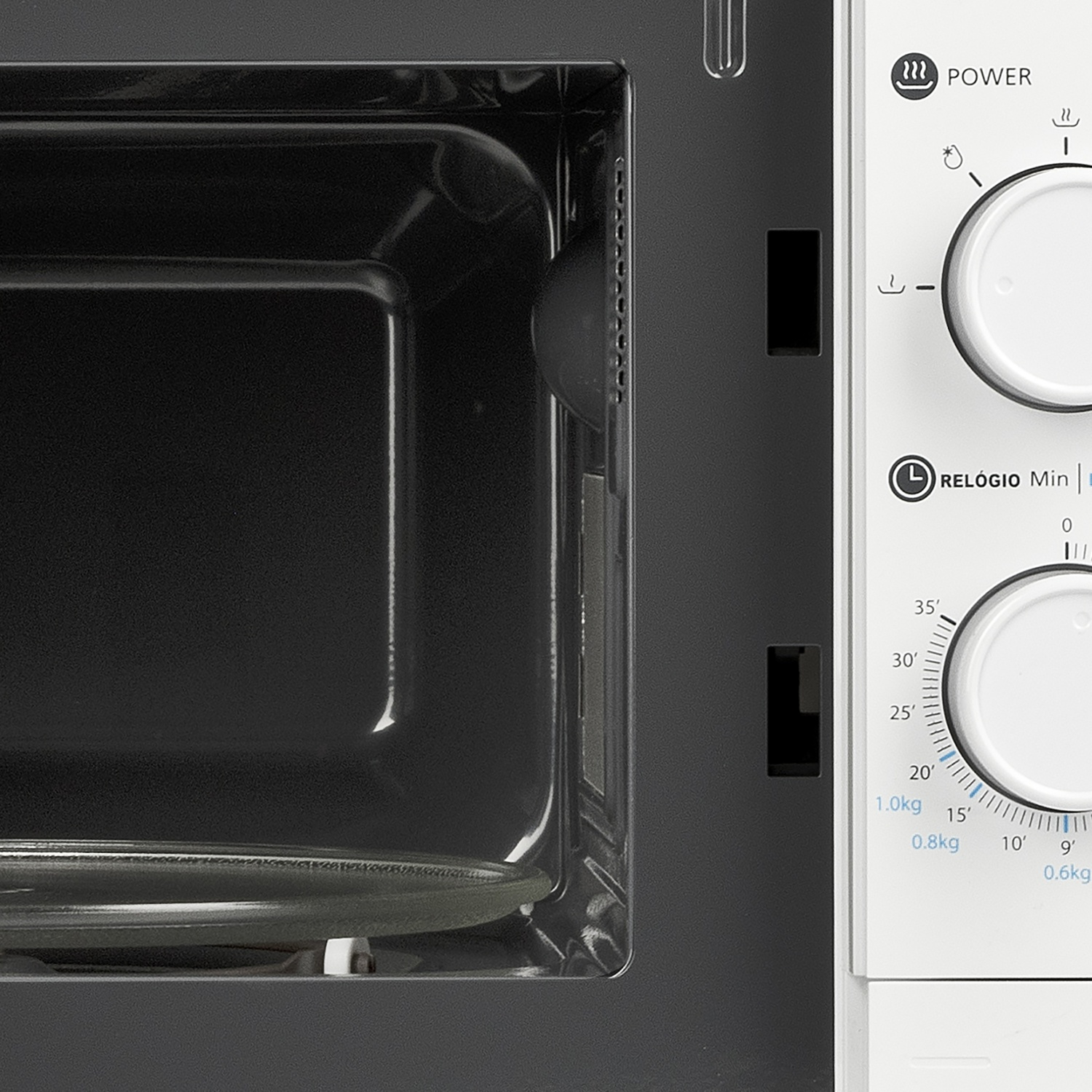 Primo piano dell'interno di un microonde bianco. L'interno è scuro, con un piatto di vetro visibile.