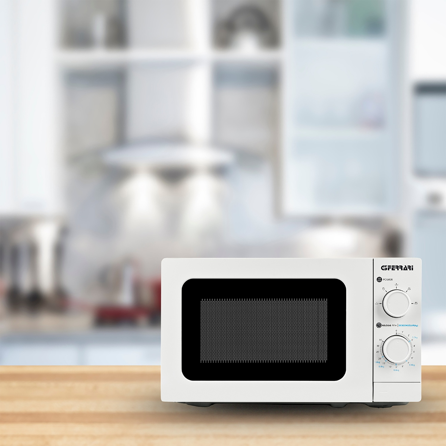 Microonde bianco su superficie in legno, con sfondo cucina sfocato.