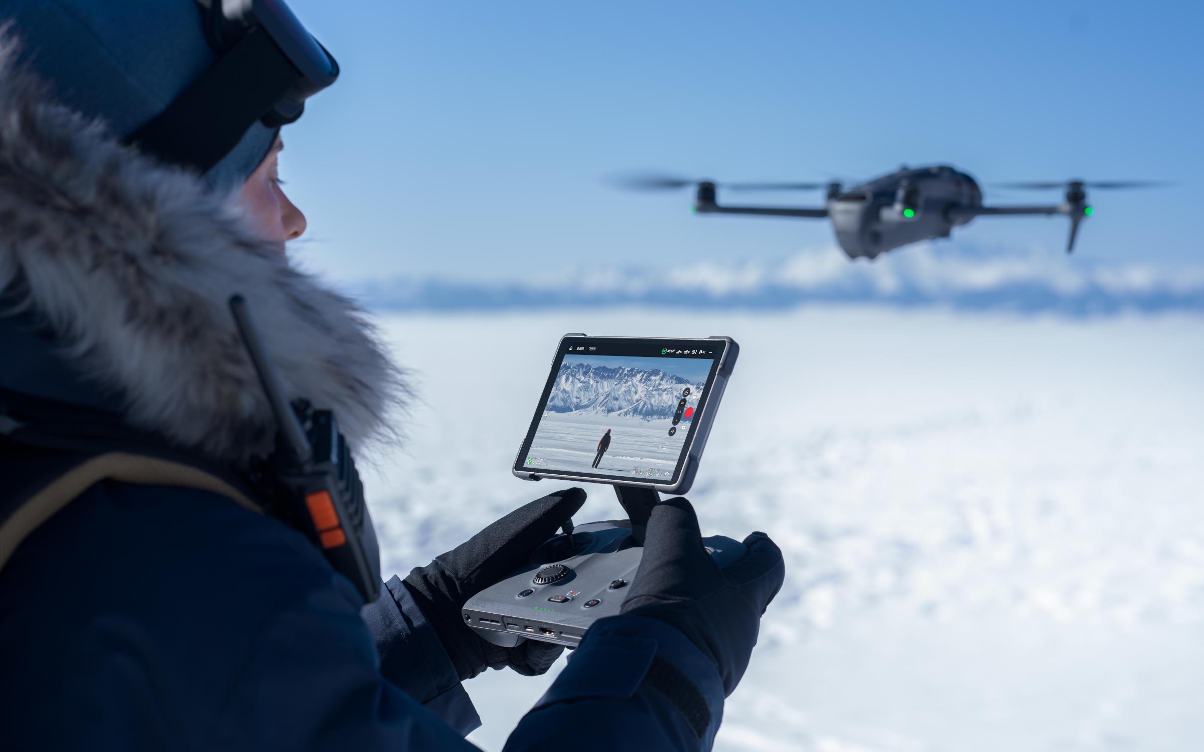 Person bedient Drohne in verschneiter Landschaft, Steuerung per Tablet.