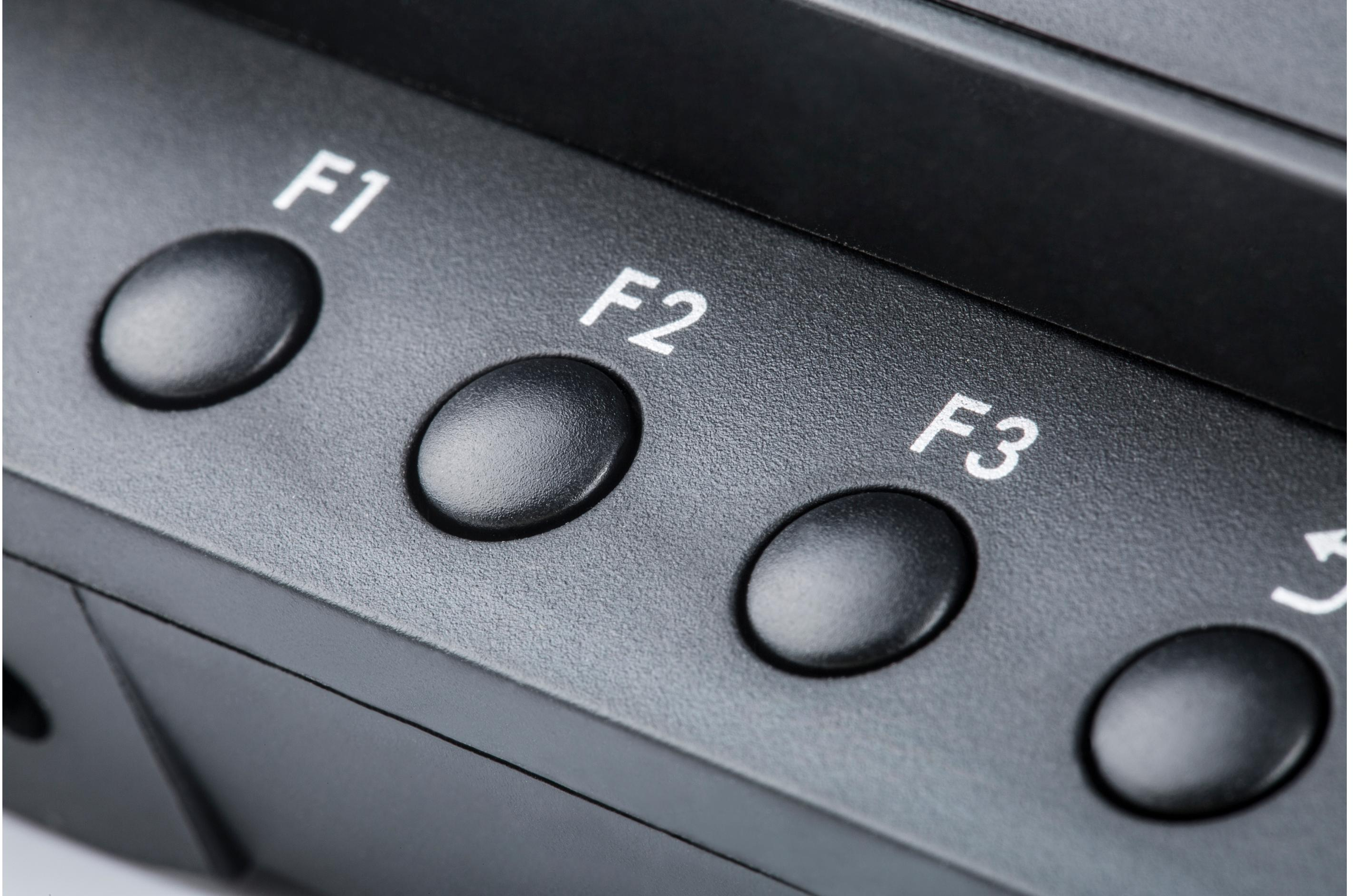 Gros plan des boutons F1, F2 et F3 sur un moniteur noir, avec une étiquette blanche.