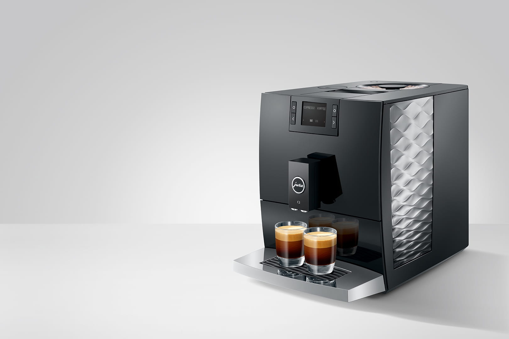 Macchina per espresso Jura nera con due bicchieri di caffè sul vassoio. Lo sfondo è bianco.