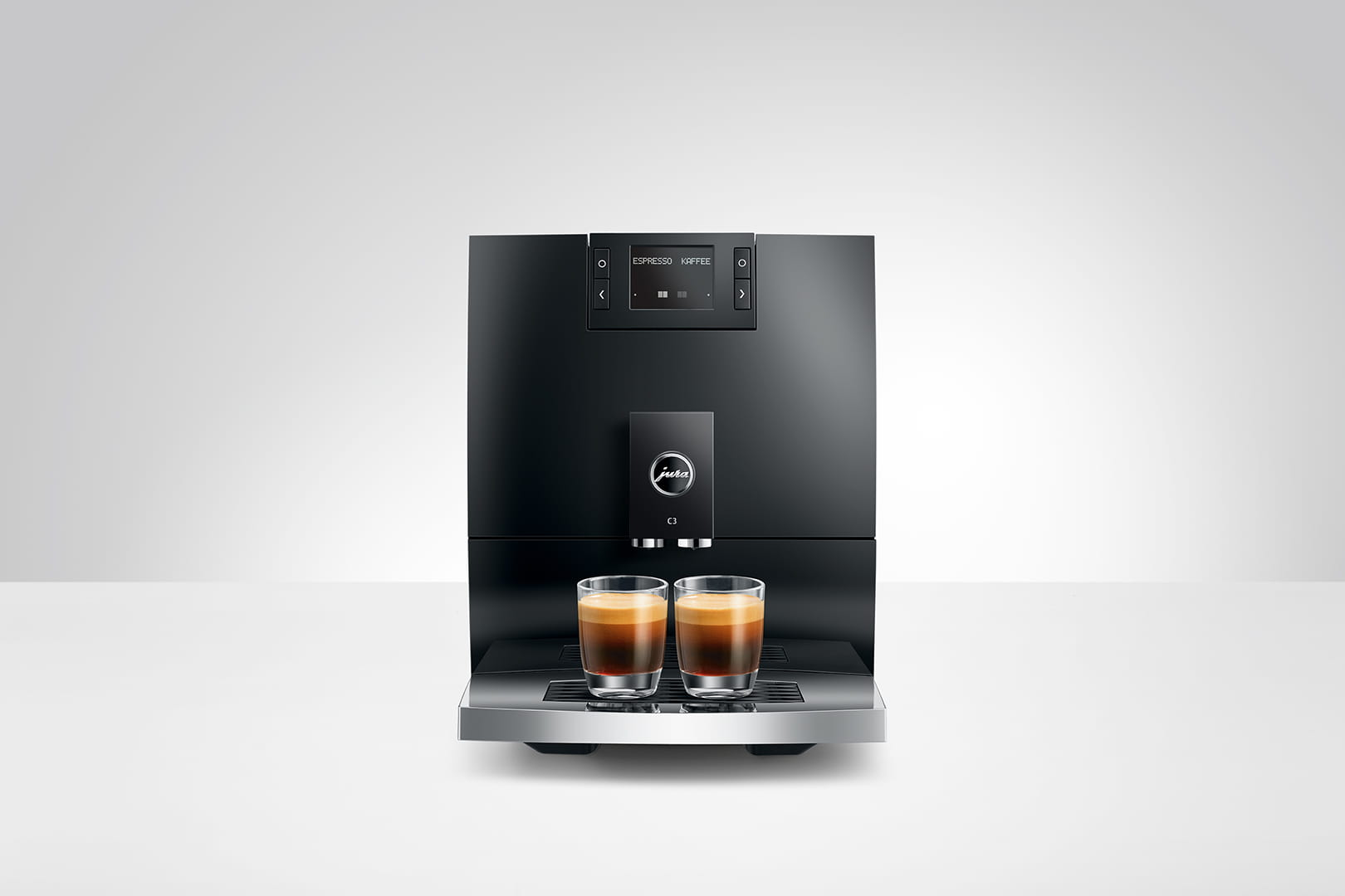 Macchina per caffè espresso nera con due bicchieri su superficie bianca.