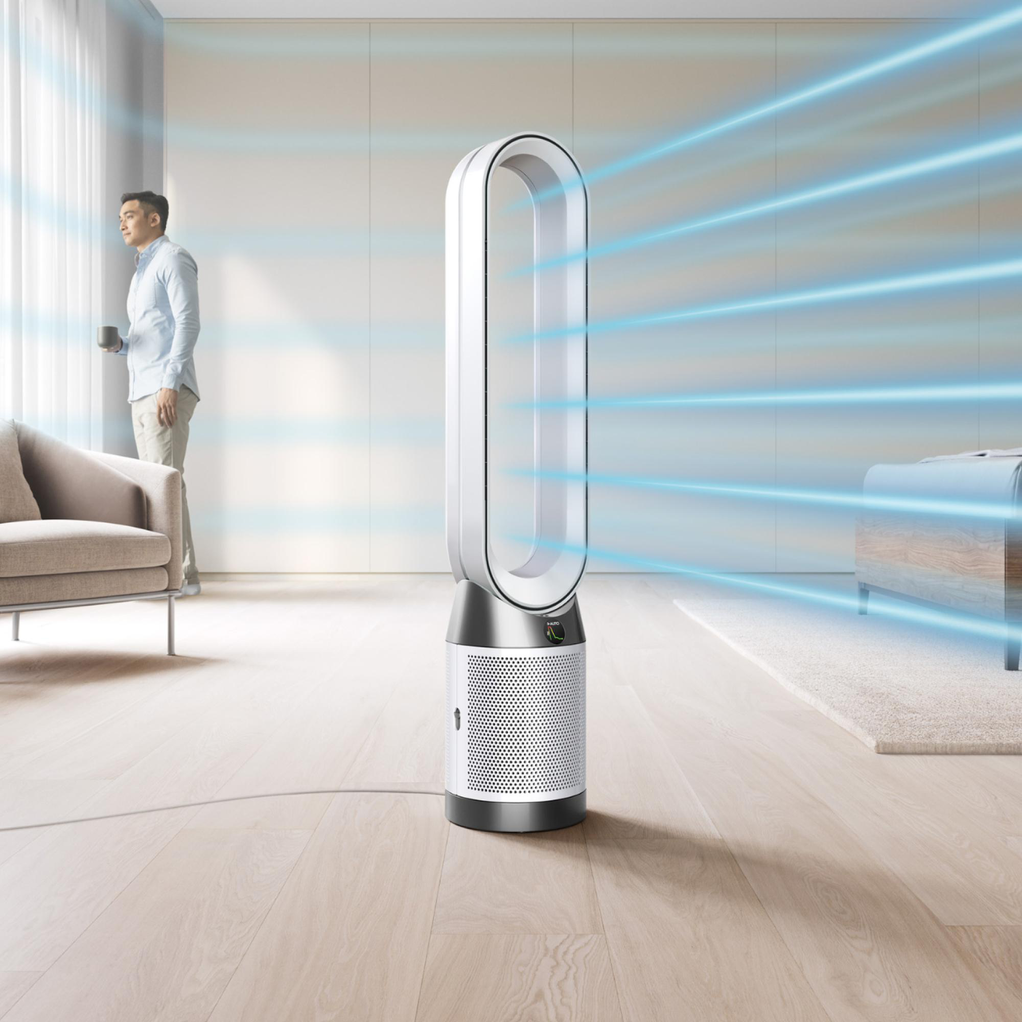 Ein Mann steht und hält eine Kaffeetasse, Dyson-Reiniger in einem Raum.