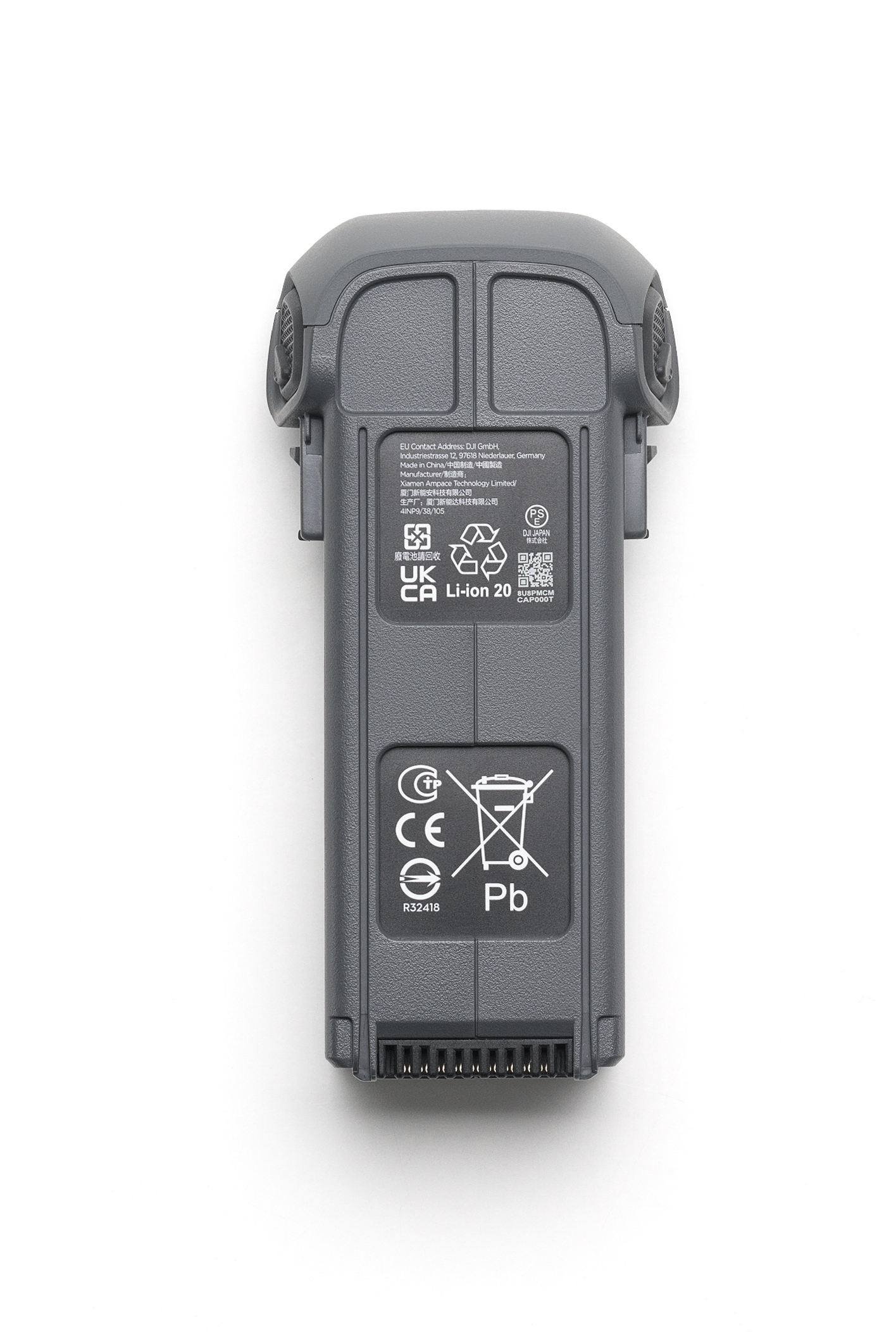 Szara bateria do drona, widoczne etykiety, białe tło. Widok z góry, pod kątem, widać górę.
