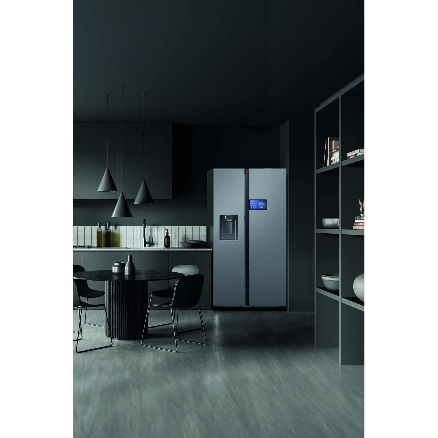 Dark kitchen with a gray refrigerator. A round table with chairs is in front. Overhead pendant lights hang.