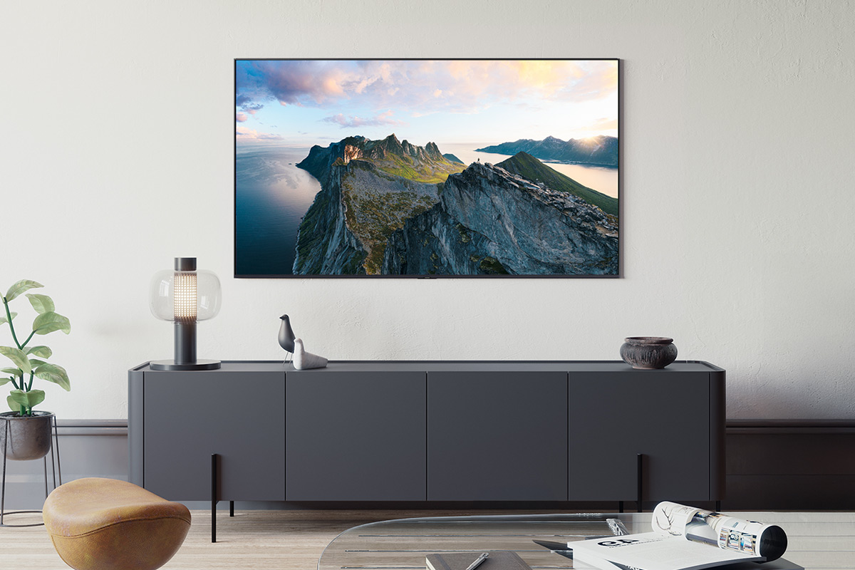 Un televisore è montato a parete, che mostra un paesaggio montano. Sotto c'è una consolle.