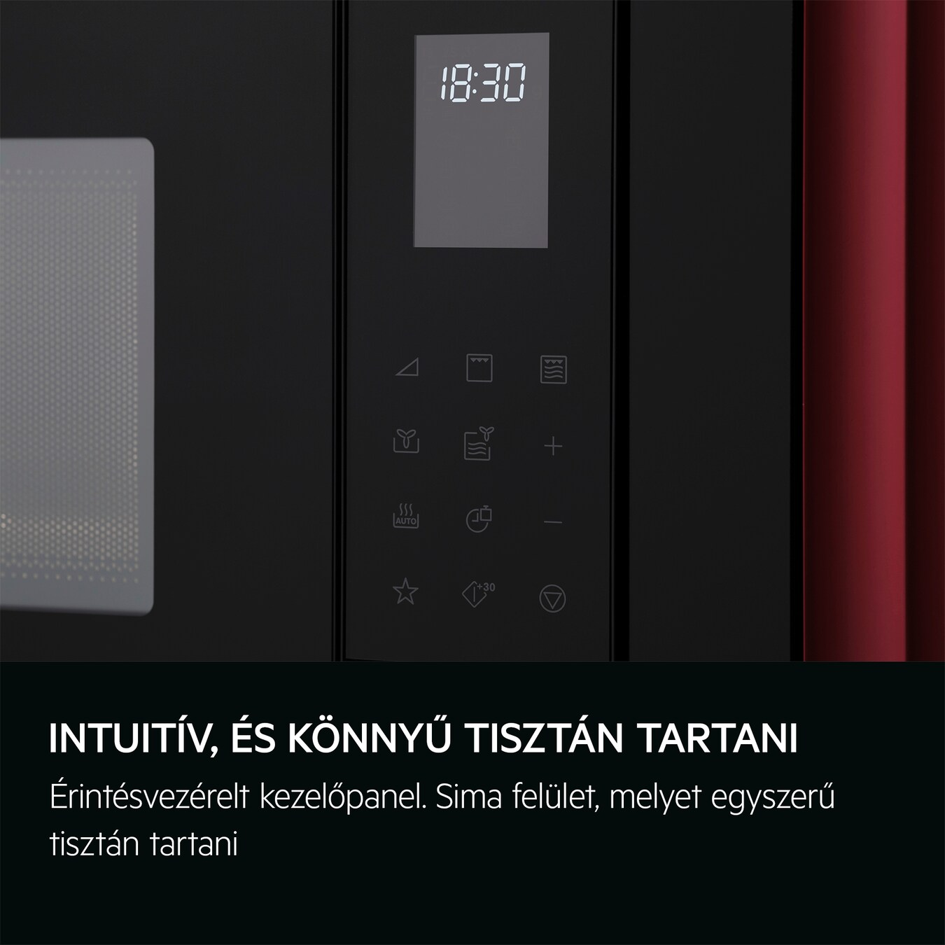 Egy személy keze egy tárcsát állít a mikrohullámú sütő vezérlőpanelén, piros háttérrel.