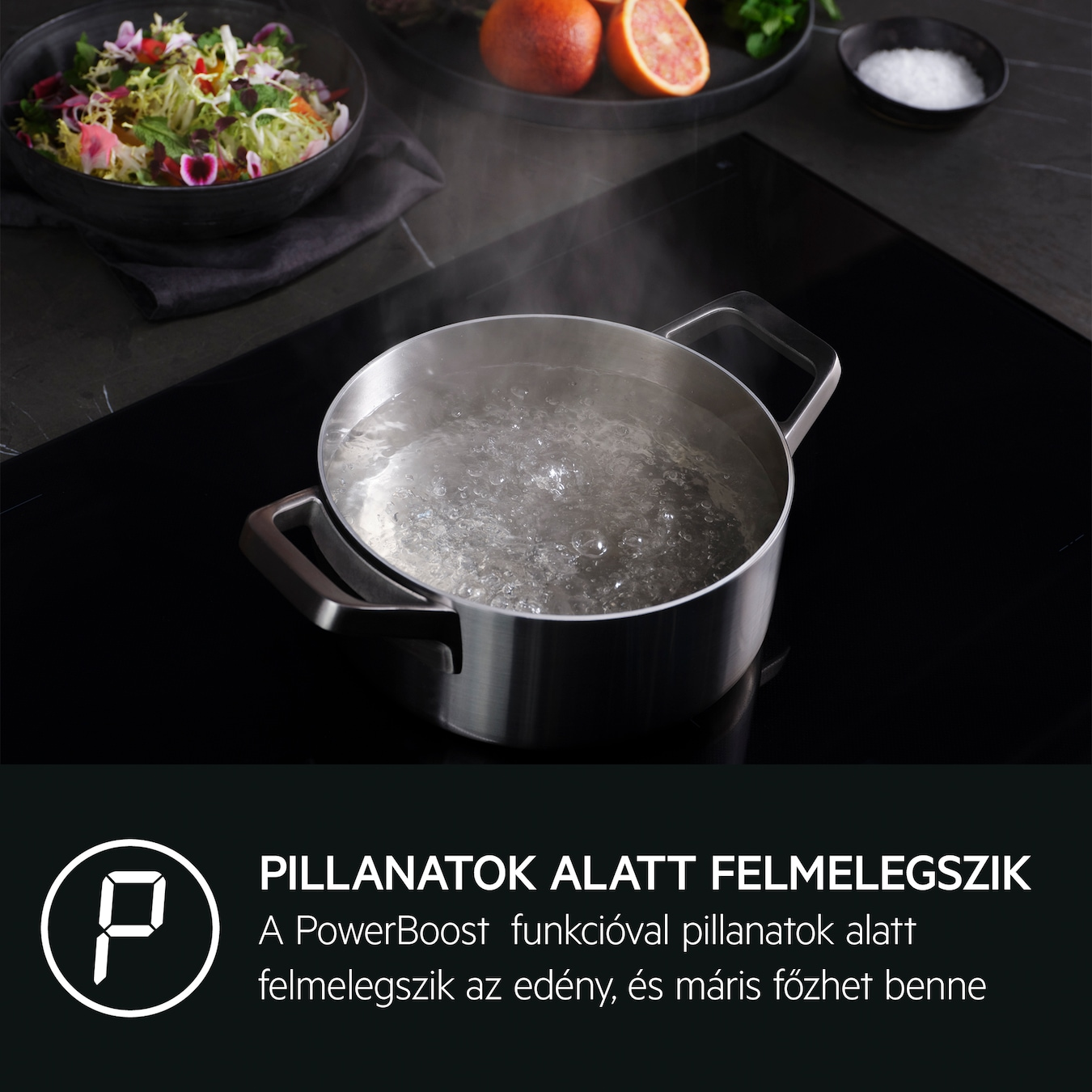 Forrásban lévő víz egy fekete főzőlapon. Saláta és gyümölcs a háttérben.