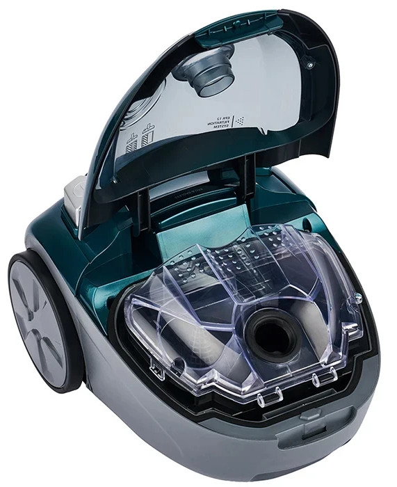 Turkusowy odkurzacz z otwartą pokrywą. Widoczny jest przedział wewnętrzny. Szara podstawa.