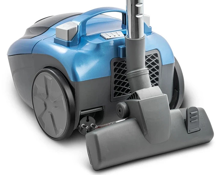 Niebieski i szary odkurzacz. Wąż i dysza znajdują się po prawej stronie.