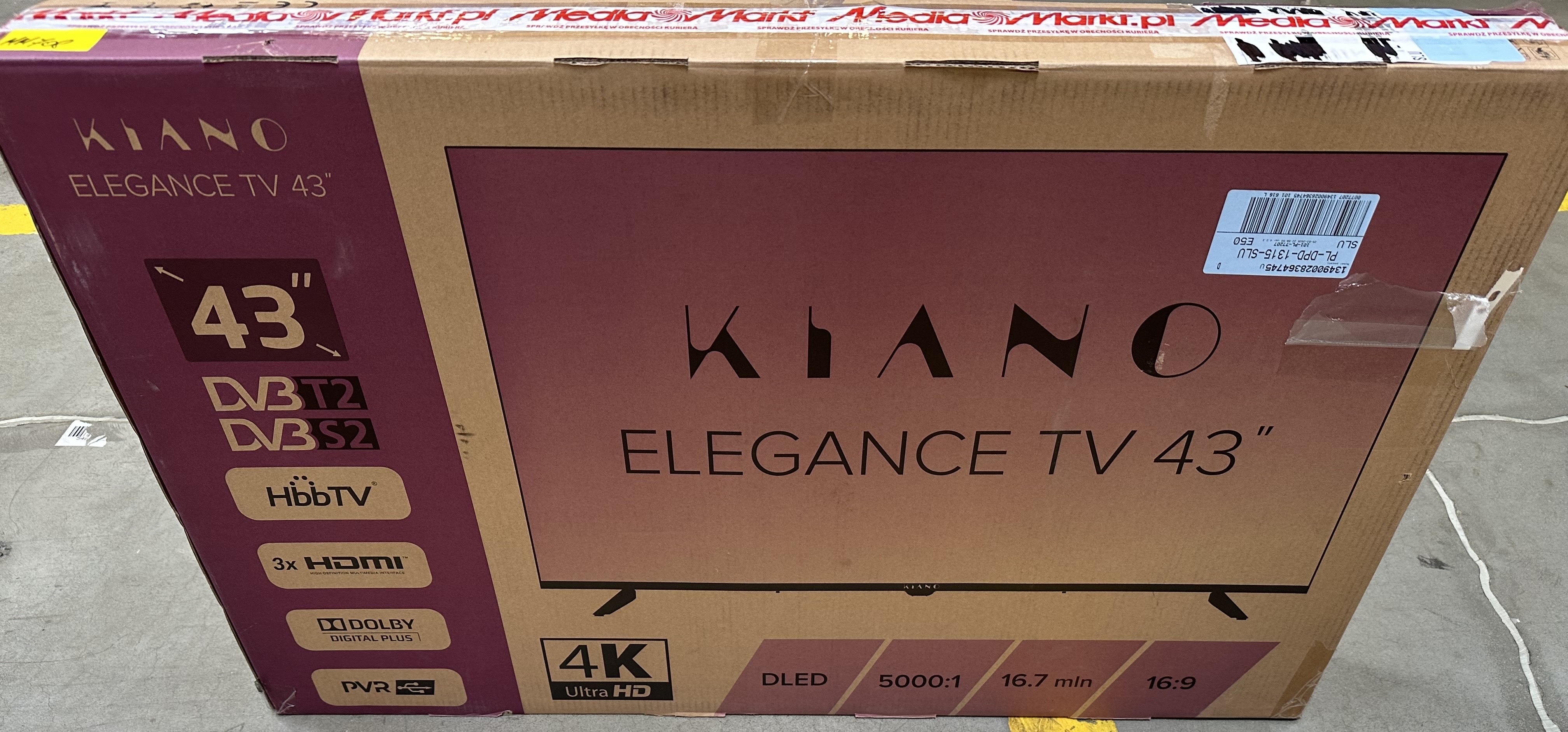Kartonowe pudełko telewizora Kiano Elegance 43". Cechy: 4K Ultra HD, HDMI i DVB-T2/S2. Pudełko jest zaklejone i opisane.