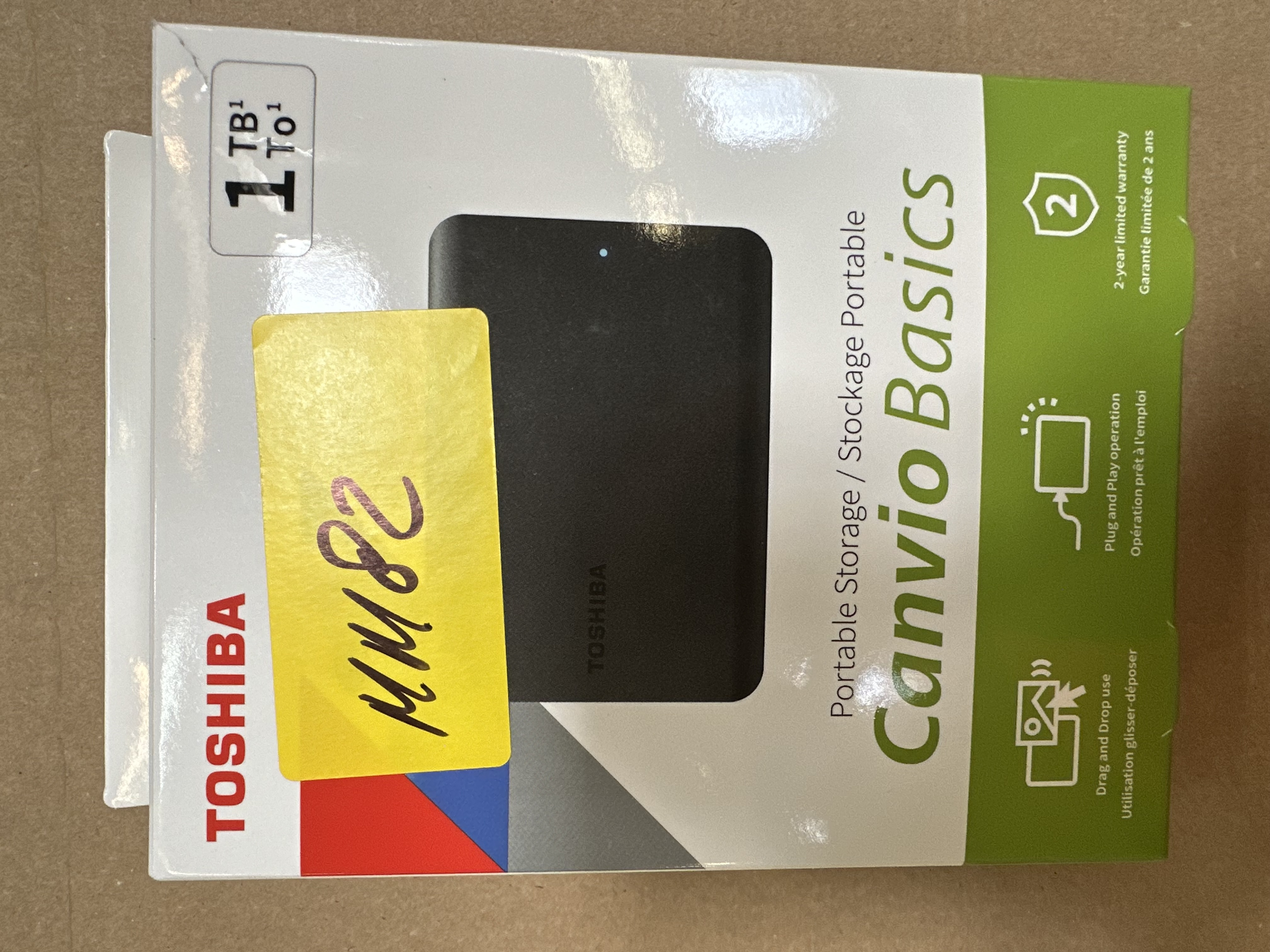 Pudełko dysku twardego Toshiba Canvio Basics 1 TB z żółtą etykietą. Tekst na pudełku zawiera szczegóły gwarancji.
