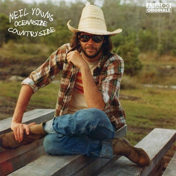 Neil Young avec un chapeau de paille, assis sur un banc en bois. Pochette d'album.
