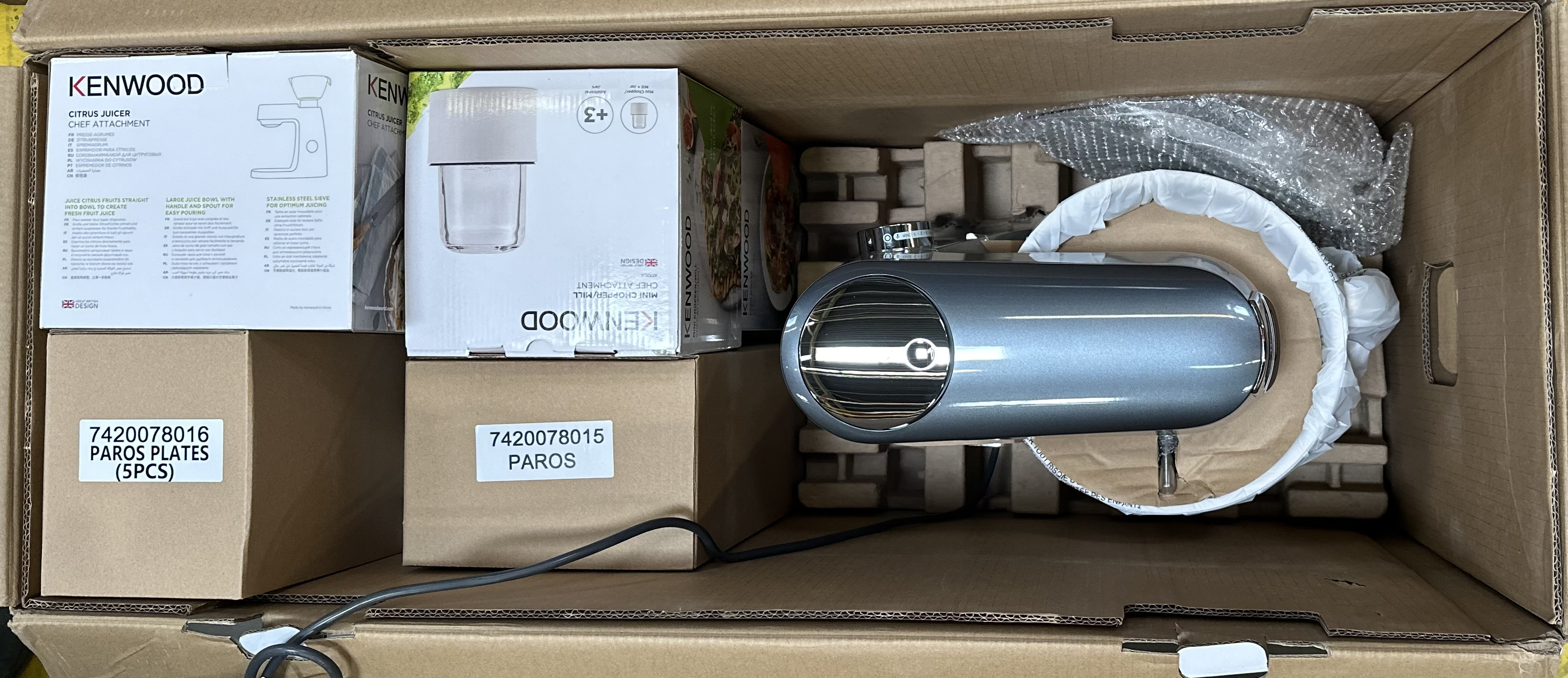 Wewnątrz kartonu znajdują się urządzenia kuchenne, w tym mikser Kenwood i pudełka z akcesoriami.