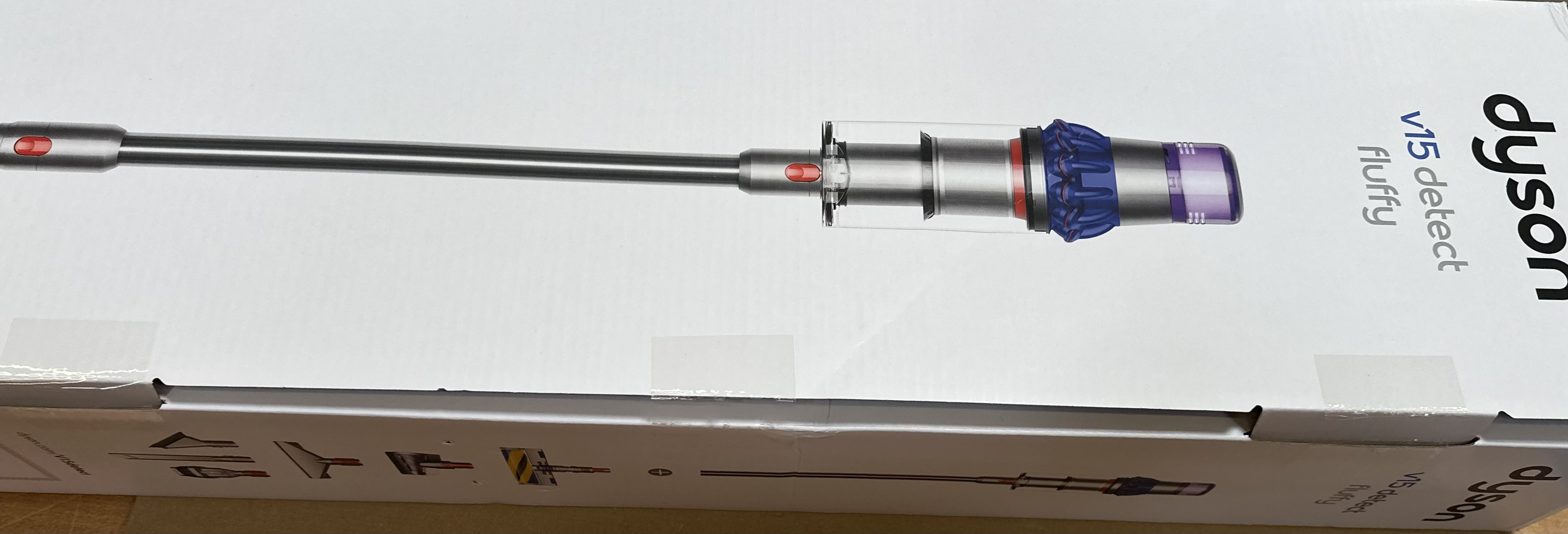 Pudełko Dyson V15 Detect Fluffy. Widoczny odkurzacz. Srebrne i fioletowe detale. Białe tło.