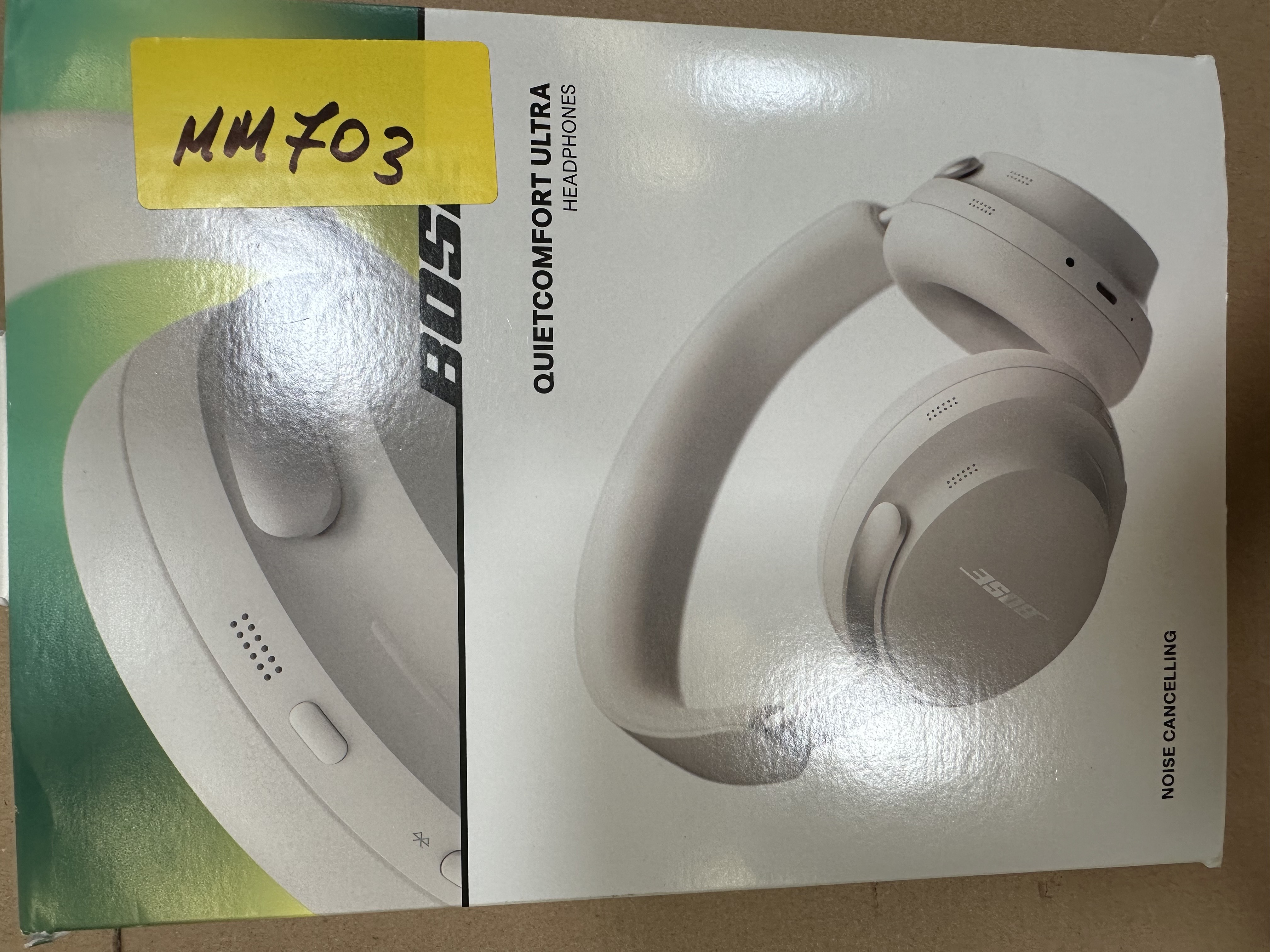 Słuchawki Bose QuietComfort Ultra na pudełku. Żółta etykieta z 'MM703'. Wyróżniona funkcja redukcji szumów.