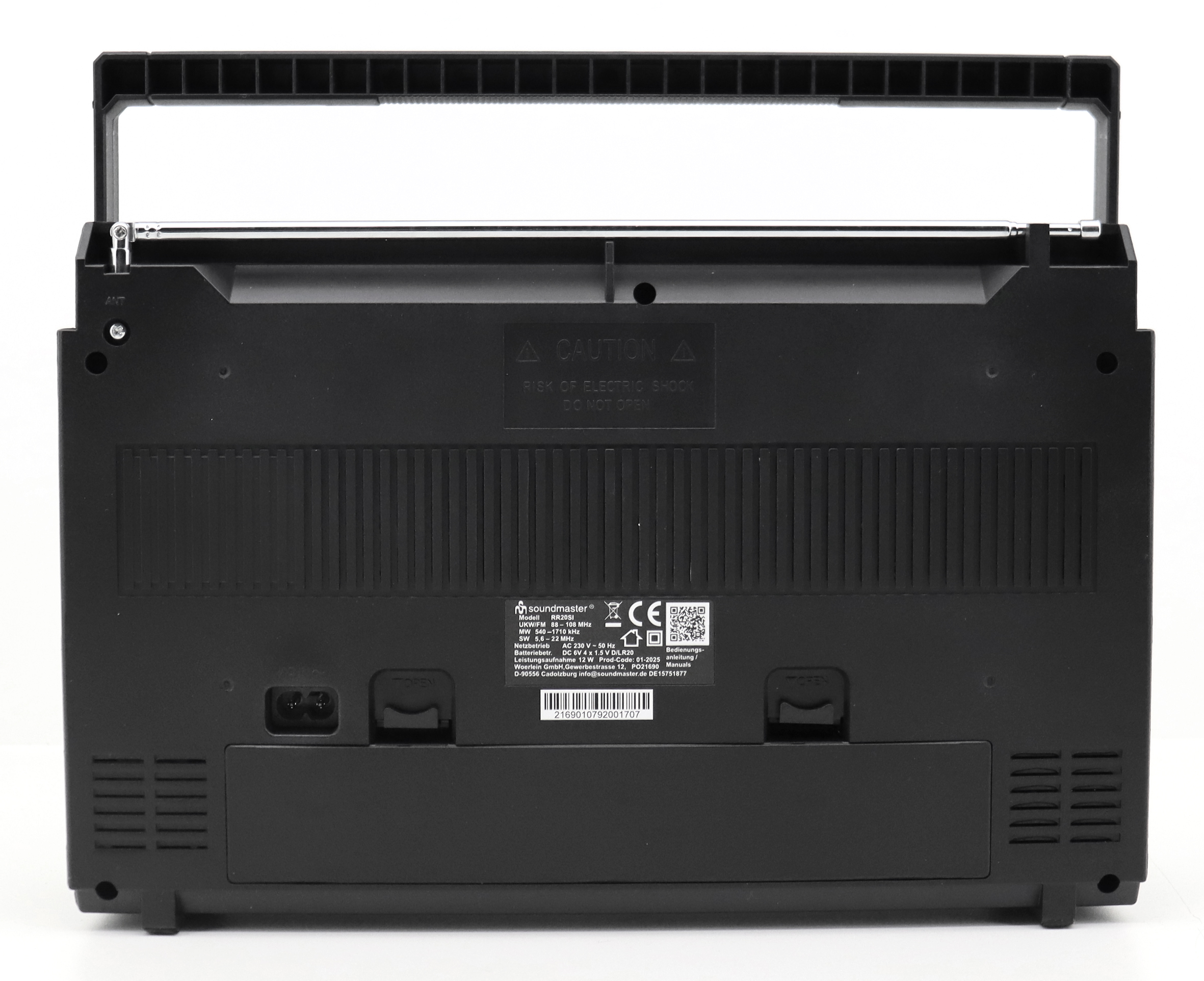 Die Rückseite einer schwarzen Boombox mit Antenne und Warnhinweisen. Es gibt einen Stromeingang und ein Batteriefach.