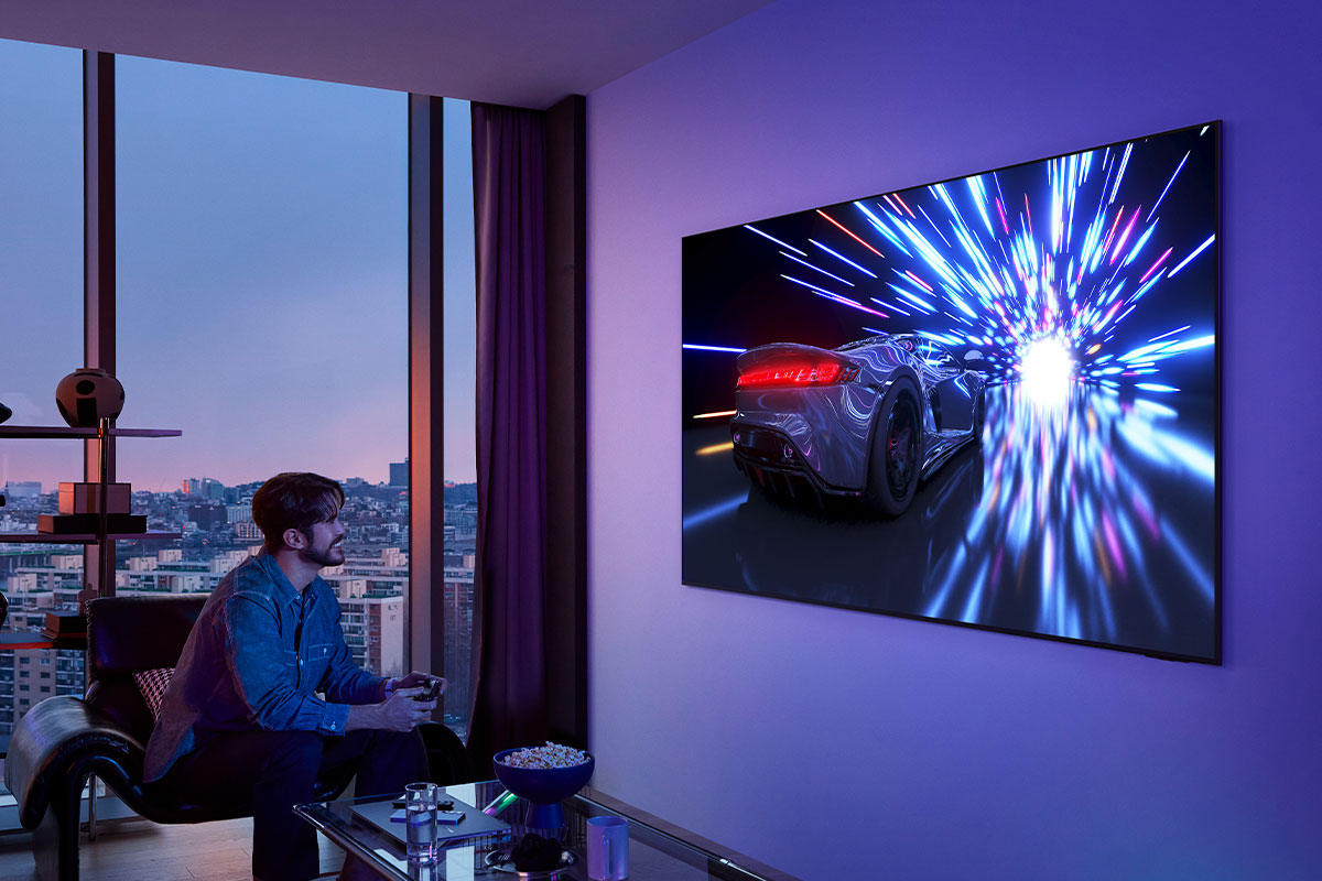 Un uomo gioca a un gioco sulla TV. La TV mostra una scena di corsa automobilistica.