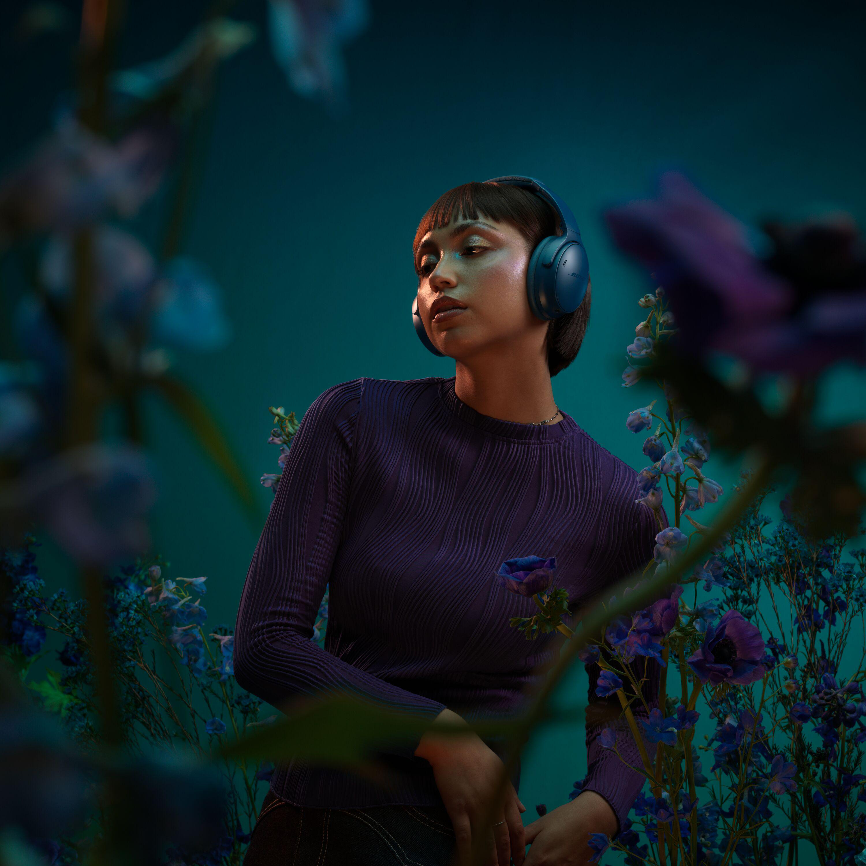 Frau mit Kopfhörern, umgeben von Blumen.